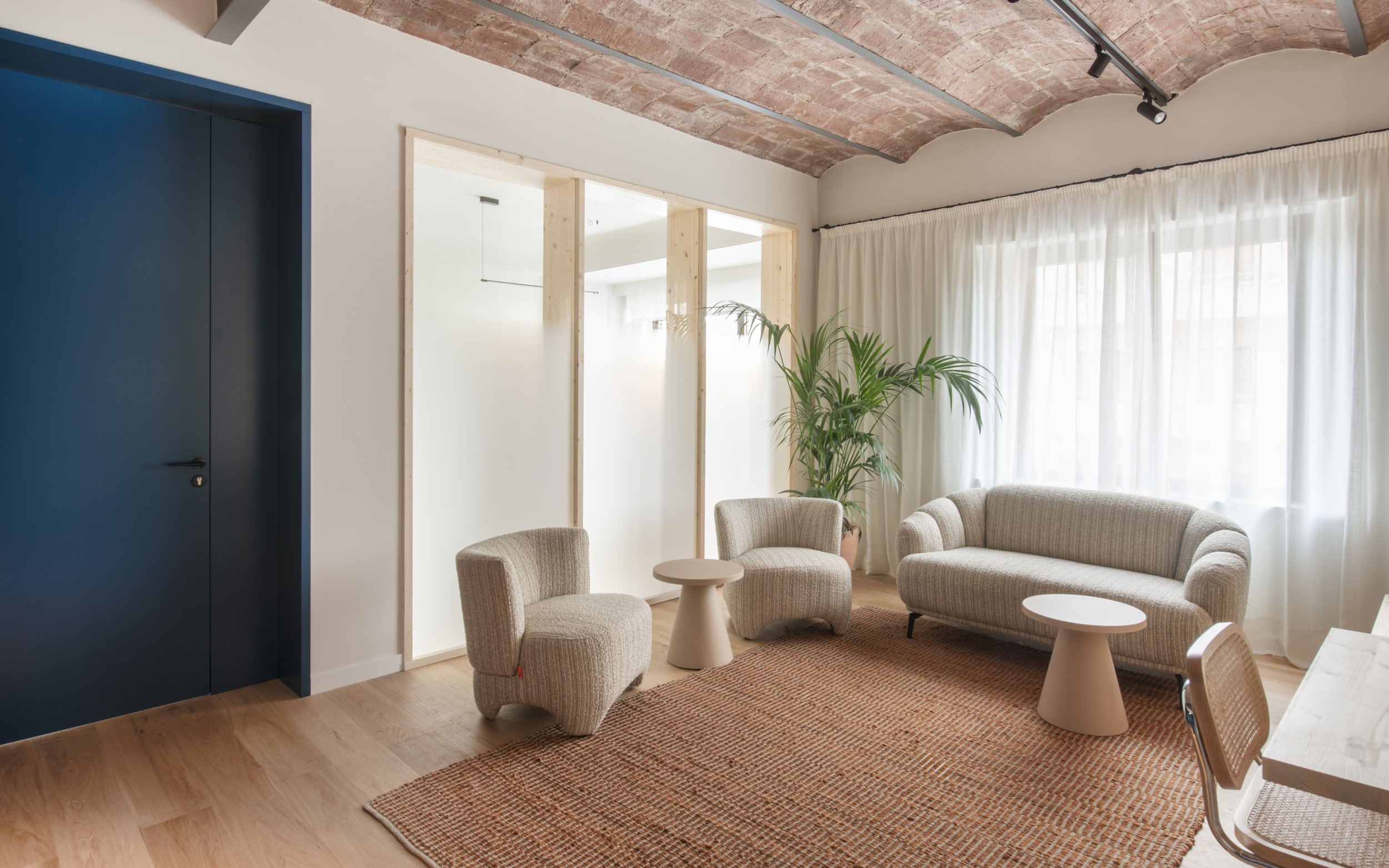 Sala íntima de Vértigo Vida con sillones, planta tropical y cortinas blancas. Atmósfera doméstica y serena en centro terapéutico de Barcelona, Escabeche Studio.