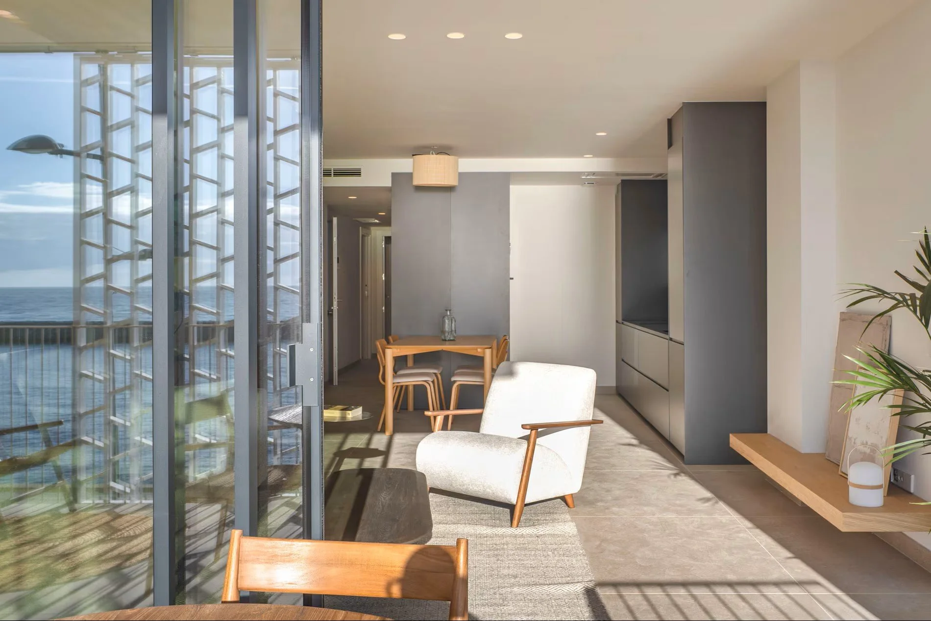 Zona de estar con sillón y acceso a terraza en apartamento de Sorra Mar i Cel, Costa Brava. Diseño que integra interior y exterior con vistas al Mediterráneo. Escabeche Studio.