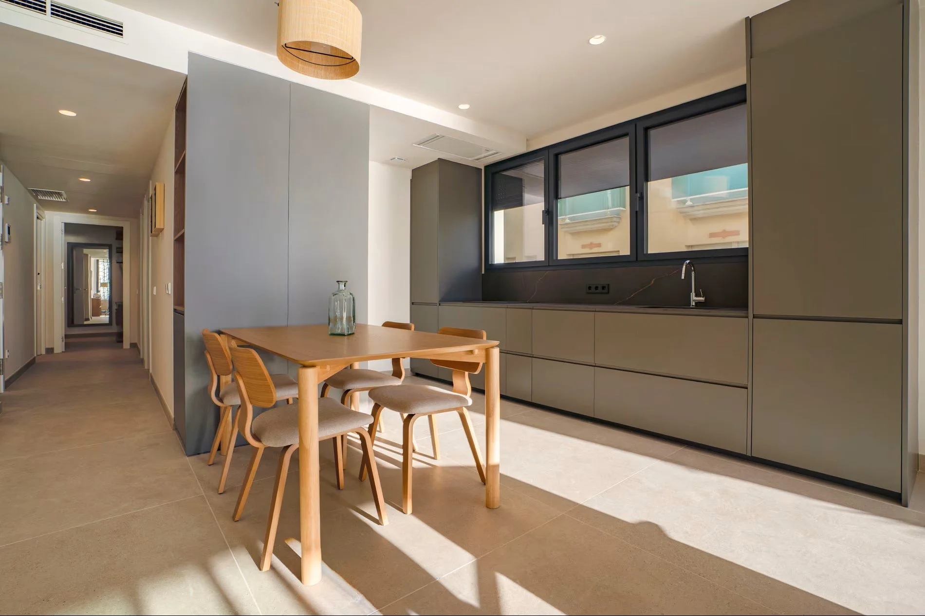 Cocina y comedor de apartamento turístico en Sorra Mar i Cel, Calonge. Mobiliario en madera natural y tonos neutros con vistas al mar. Proyecto de interiorismo de Escabeche Studio.