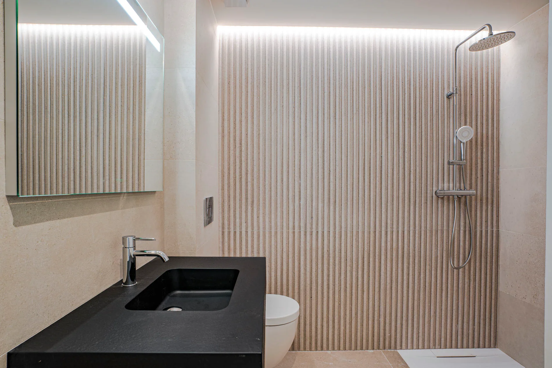 Baño de apartamento turístico en Sorra Mar i Cel con lavabo negro, revestimiento de lamas y ducha. Acabados de calidad en proyecto hospitality de Escabeche Studio, Calonge.
