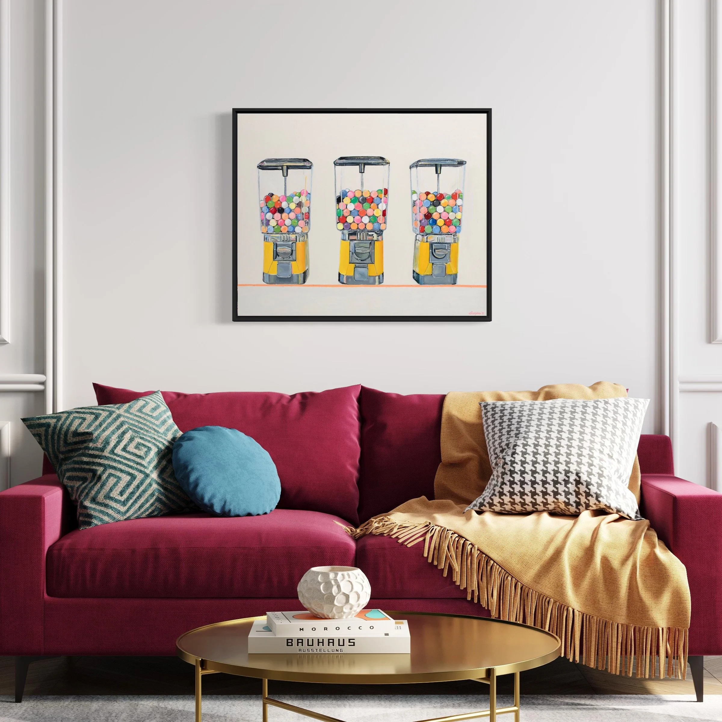 Living room with a pink sofa, colorful pillows, and a gold coffee table, with a framed picture of gumball machines on the wall above.