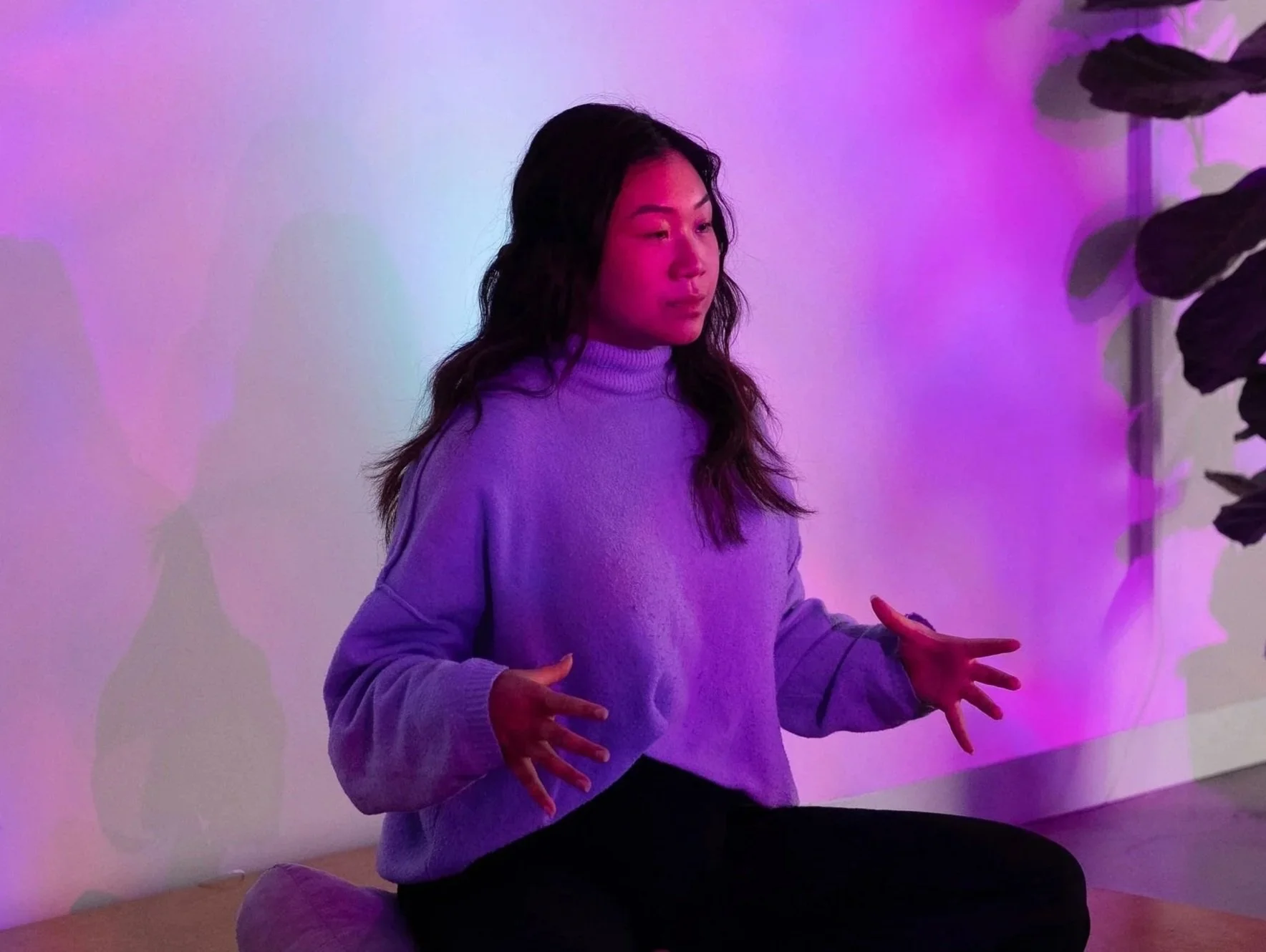 Liz Ho guiding participants through a breathwork practice at No Name Studios under purple lighting.