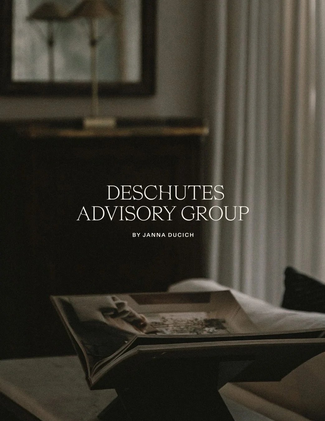 Cover of a publication titled 'Deschutes Advisory Group' by Janna Ducich. The cover features a dark interior scene with a table, an open magazine, and part of a lamp and curtain visible in the background.