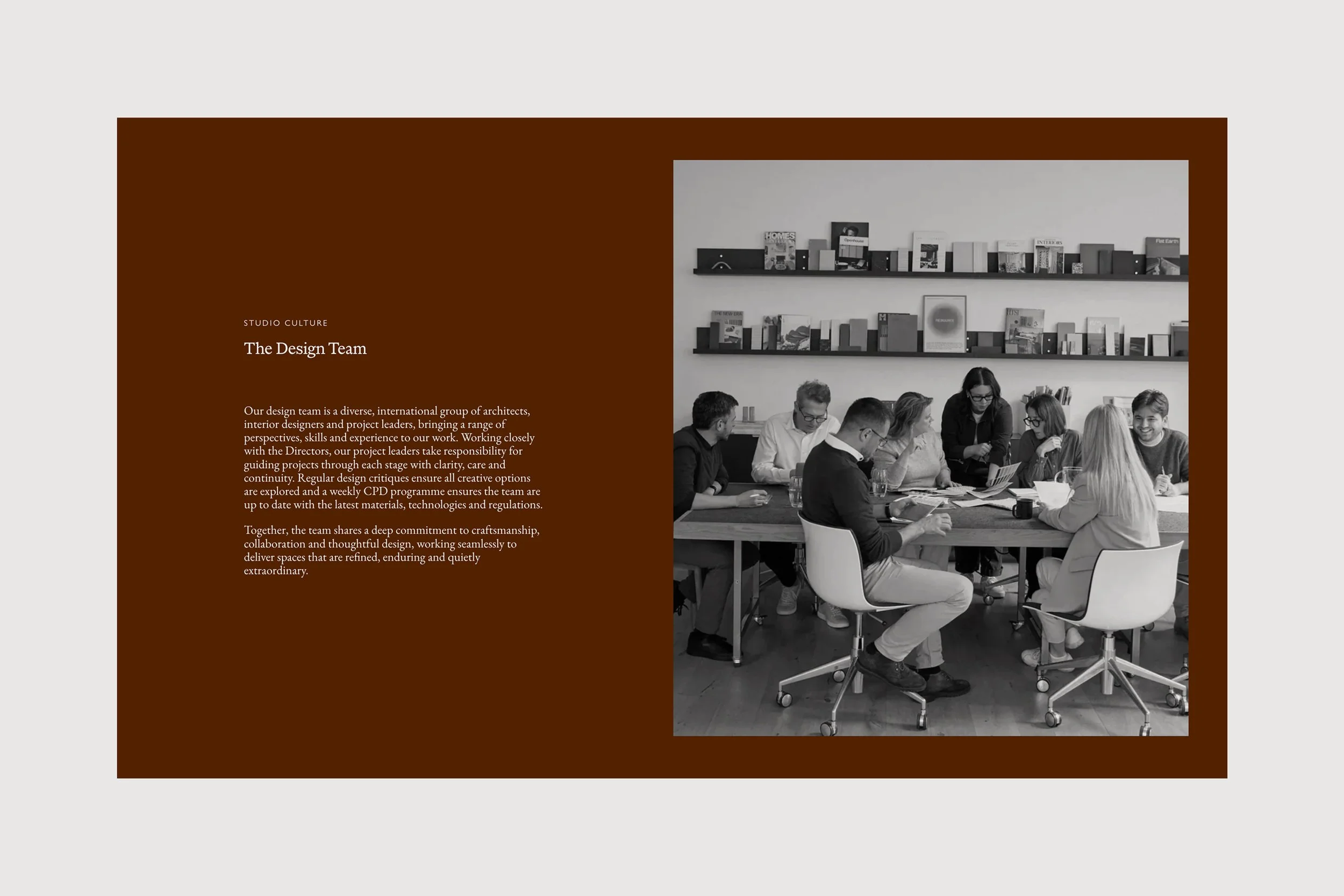 A group of diverse people sitting around a table in a meeting room, engaged in a discussion, with bookshelves on the wall behind them.