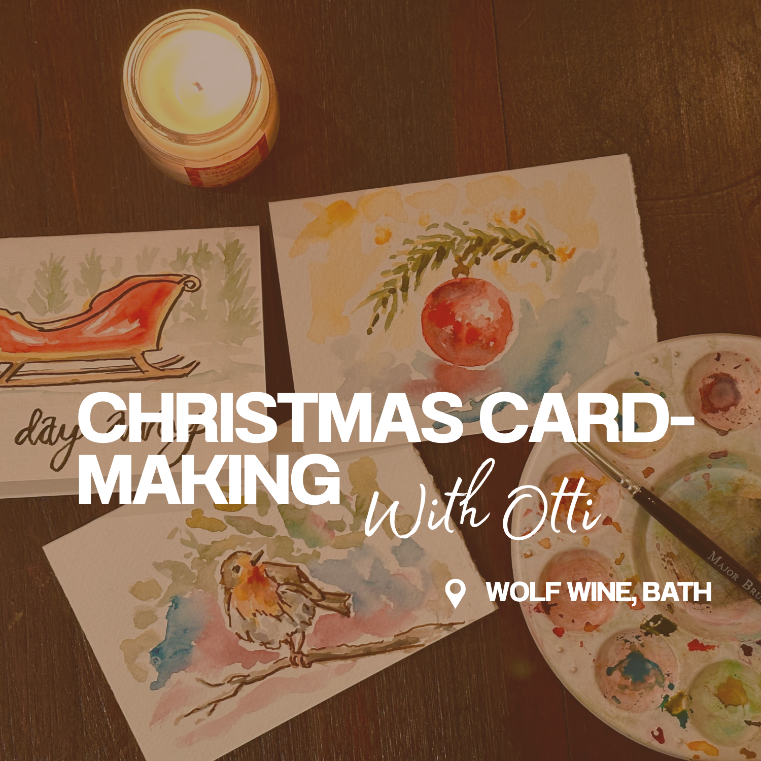 Watercolor Christmas cards, a lit candle, used watercolor palette, and brush on a wooden table.