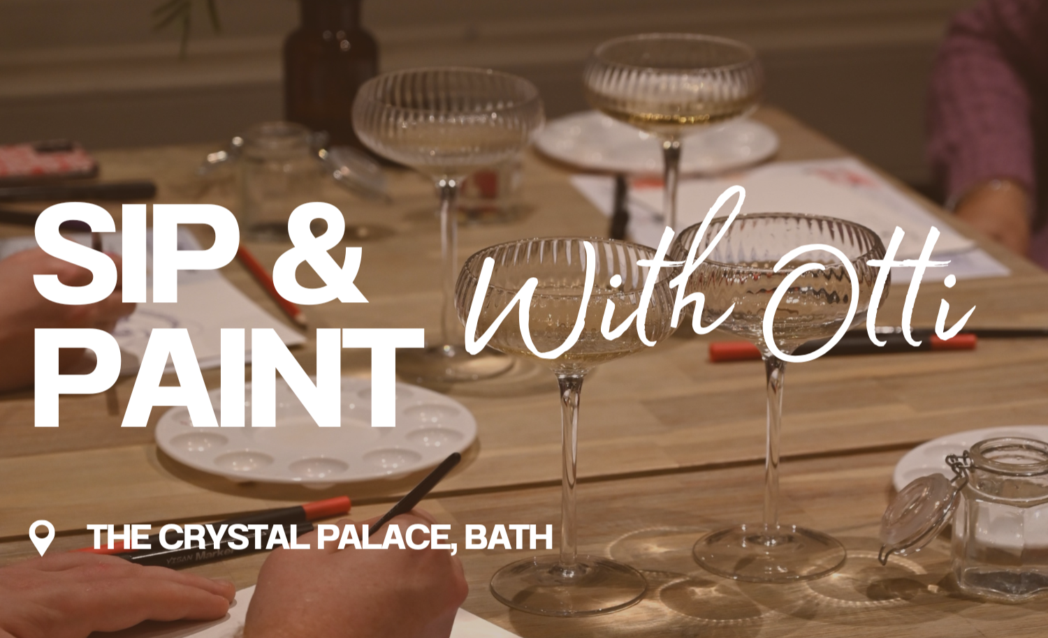 A table set for a tasting event with empty wine glasses, a paint palette, and a person's hands holding a pen, with the event title 'Sip & Paint Without OTTi' at The Crystal Palace, Bath.