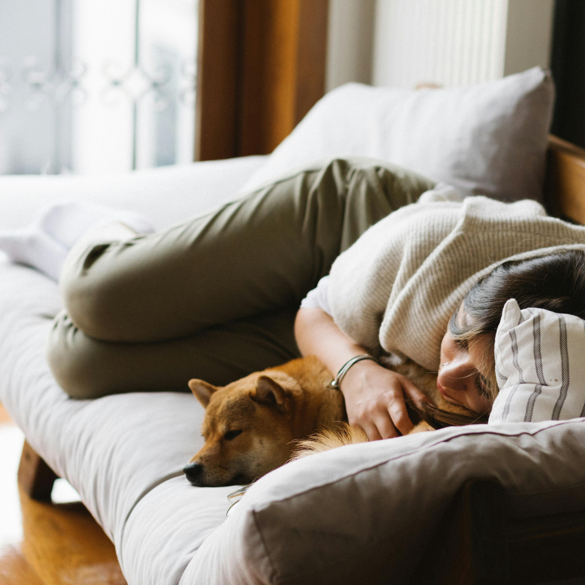 Physical rest - A woman lying on a bed hugging a brown dog, both resting peacefully.
