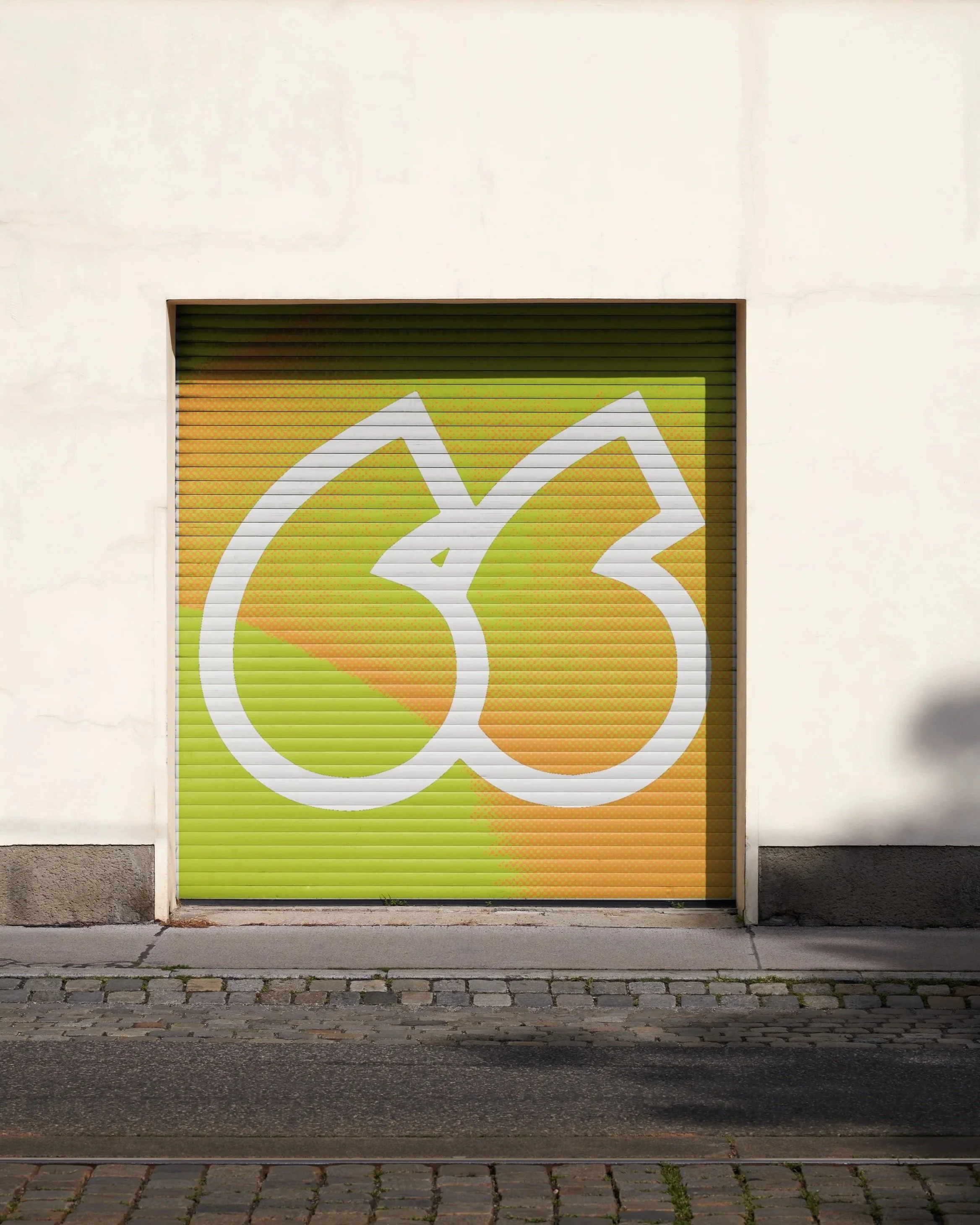 A white building with a yellow, green, and orange abstract graphic painted on a metal rolling door.