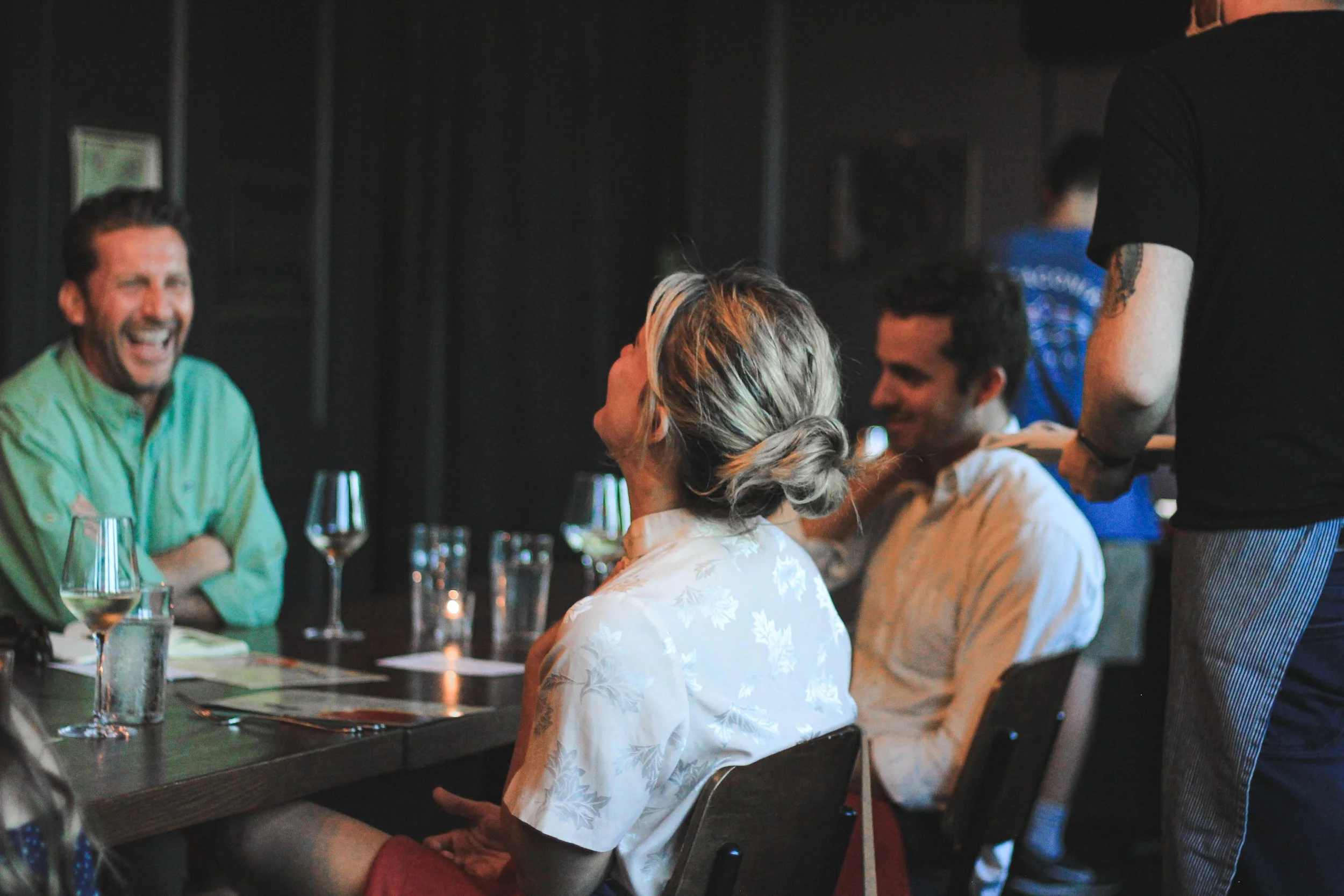 group laughs during special event dinner photography by Caleb quire