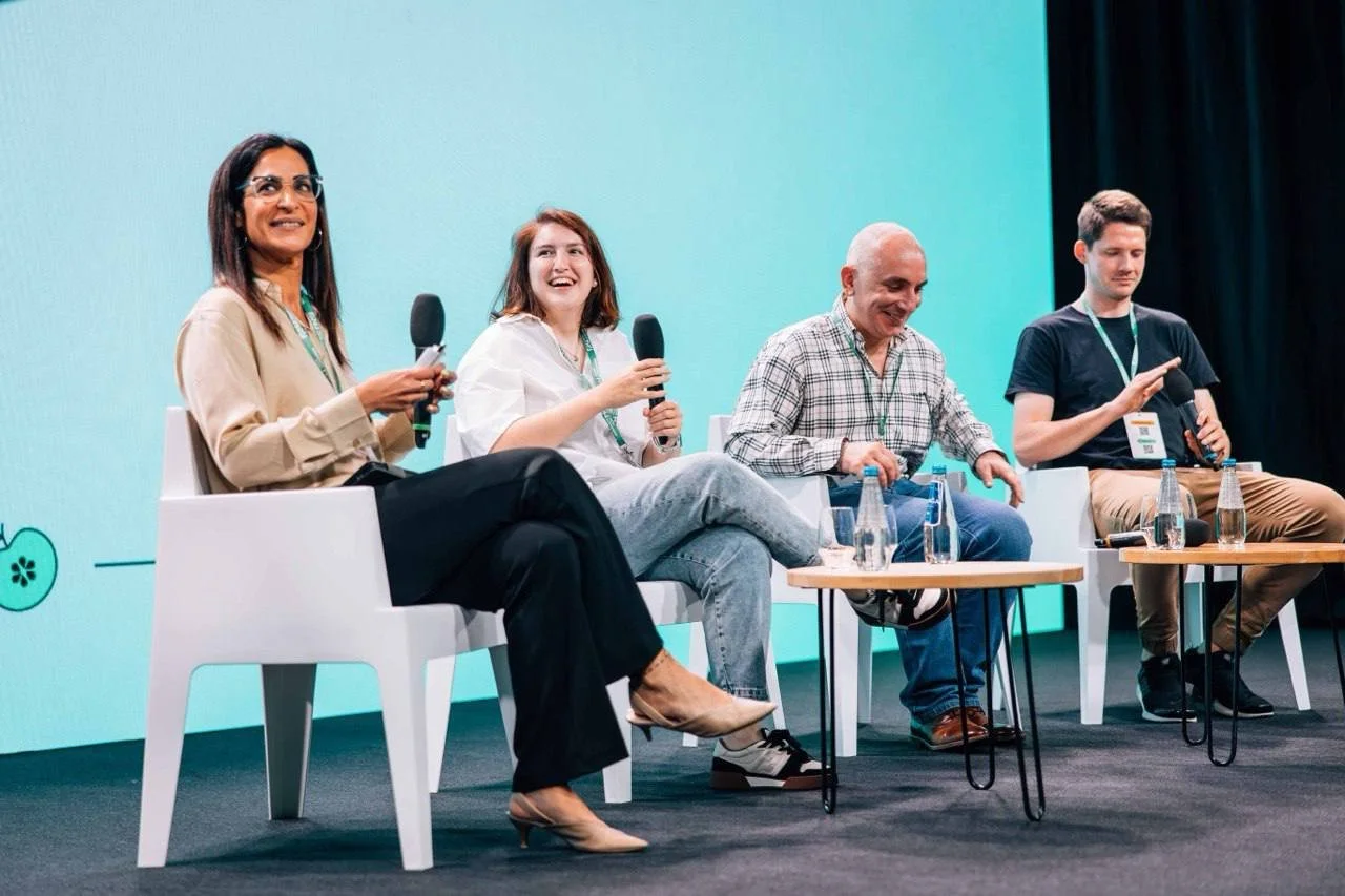 Four people sitting on stage holding microphones at a panel discussion or conference.