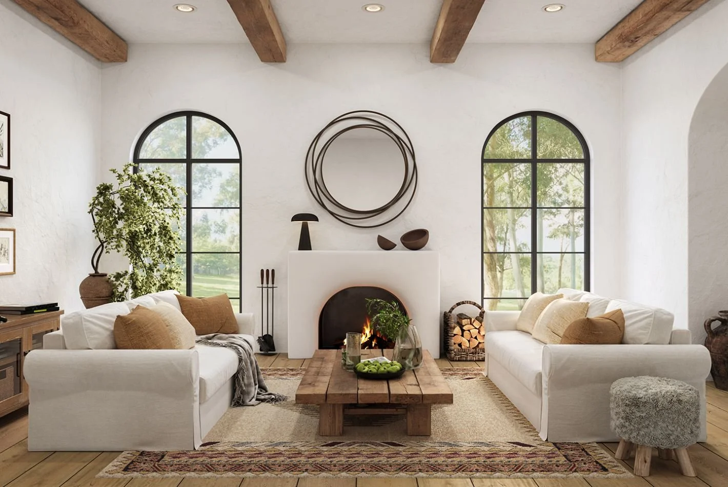 Living room with white sofas, a rustic wood coffee table, a fireplace with firewood, large arched windows, and decorative wall art. Natural light illuminates the space with wooden beams on the ceiling.