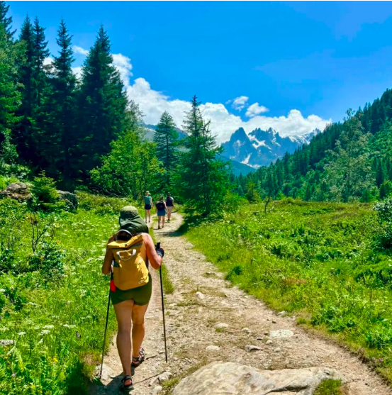 Hikers on a mountain trail towards snowy peaks near Chamonix, French Alps