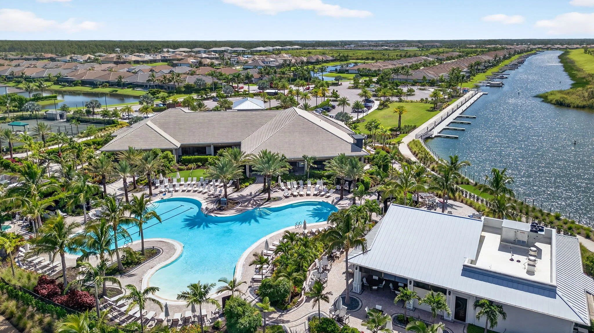 Cinematic drone shot of resort property by VisionBoost Studios — large pool, palm trees, docked boats, and canal view.