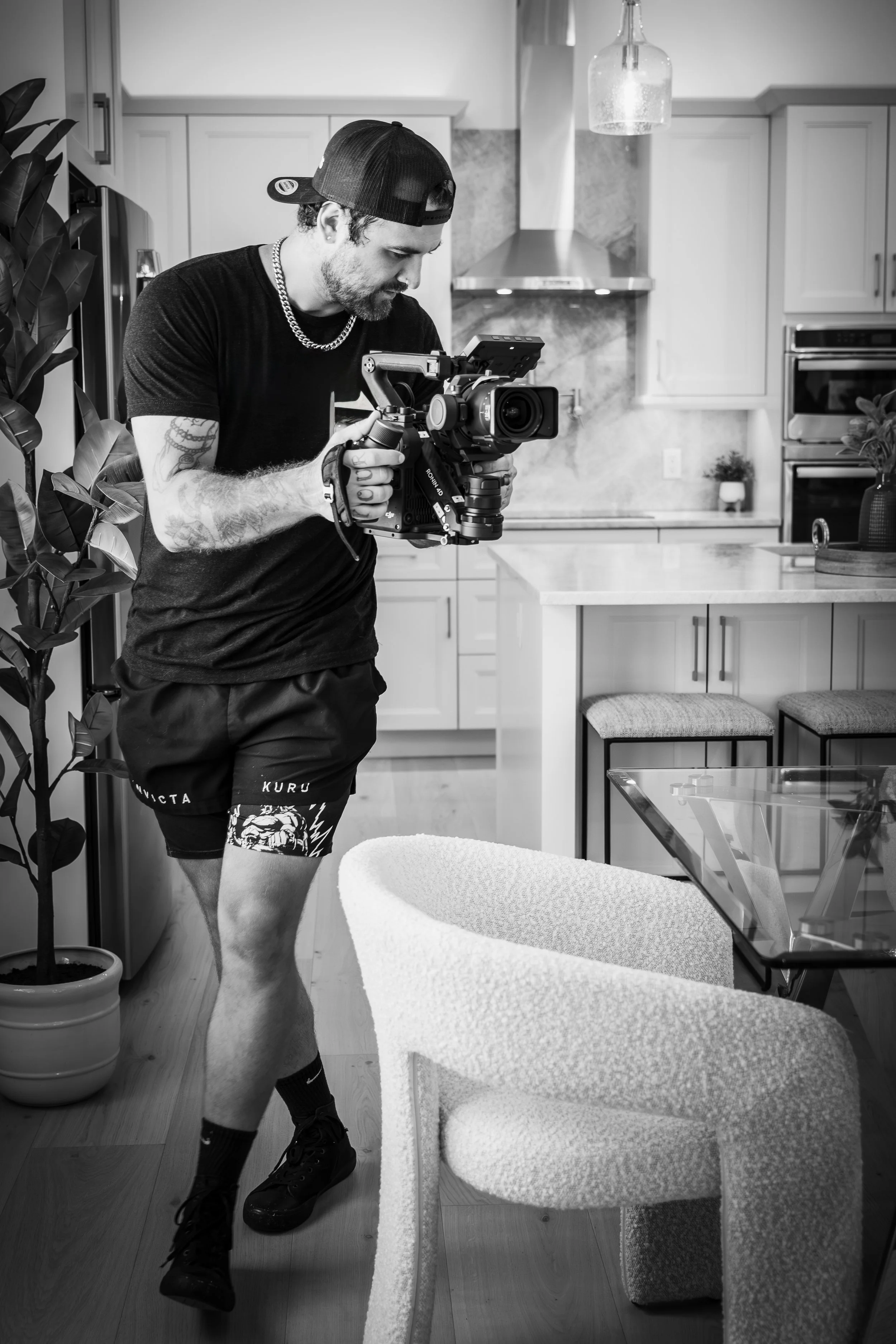 Real estate videographer from VisionBoost Studios filming cinematic content in a modern kitchen using professional video gear.