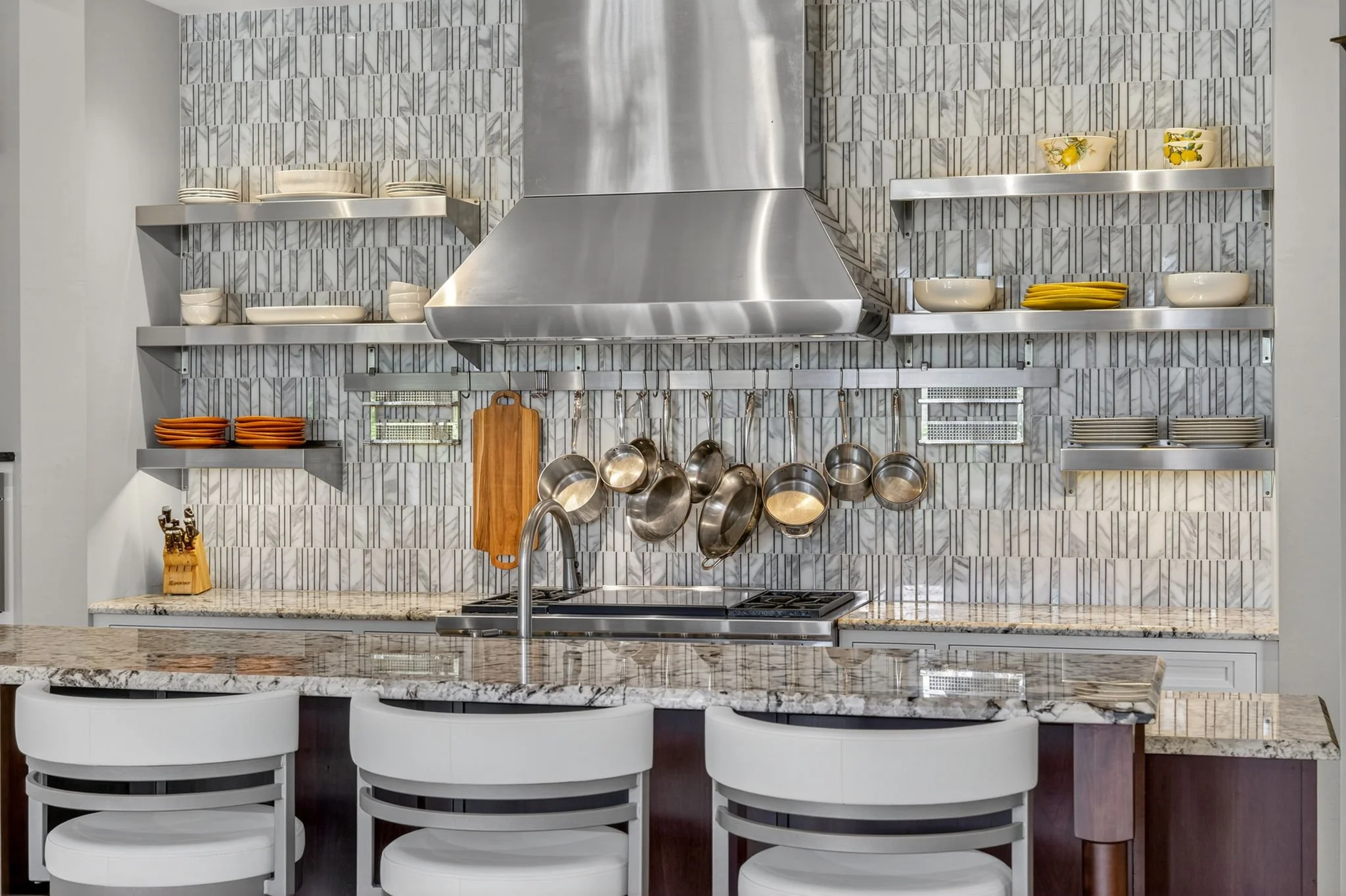 Professional kitchen photo by VisionBoost Studios showing open shelving, hanging pots, and luxury marble countertops.