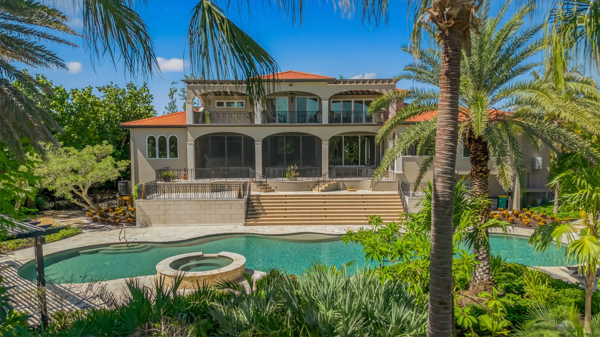 High-end real estate listing captured by VisionBoost Studios featuring a red-tiled roof, swimming pool, and palm landscaping