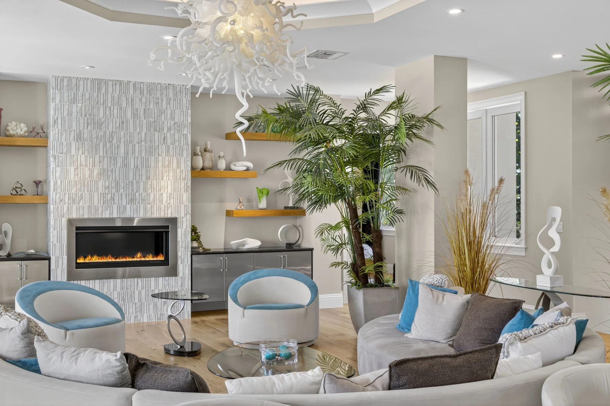 Real estate interior image by VisionBoost Studios — curved sofa, accent chairs, modern décor, and natural lighting.