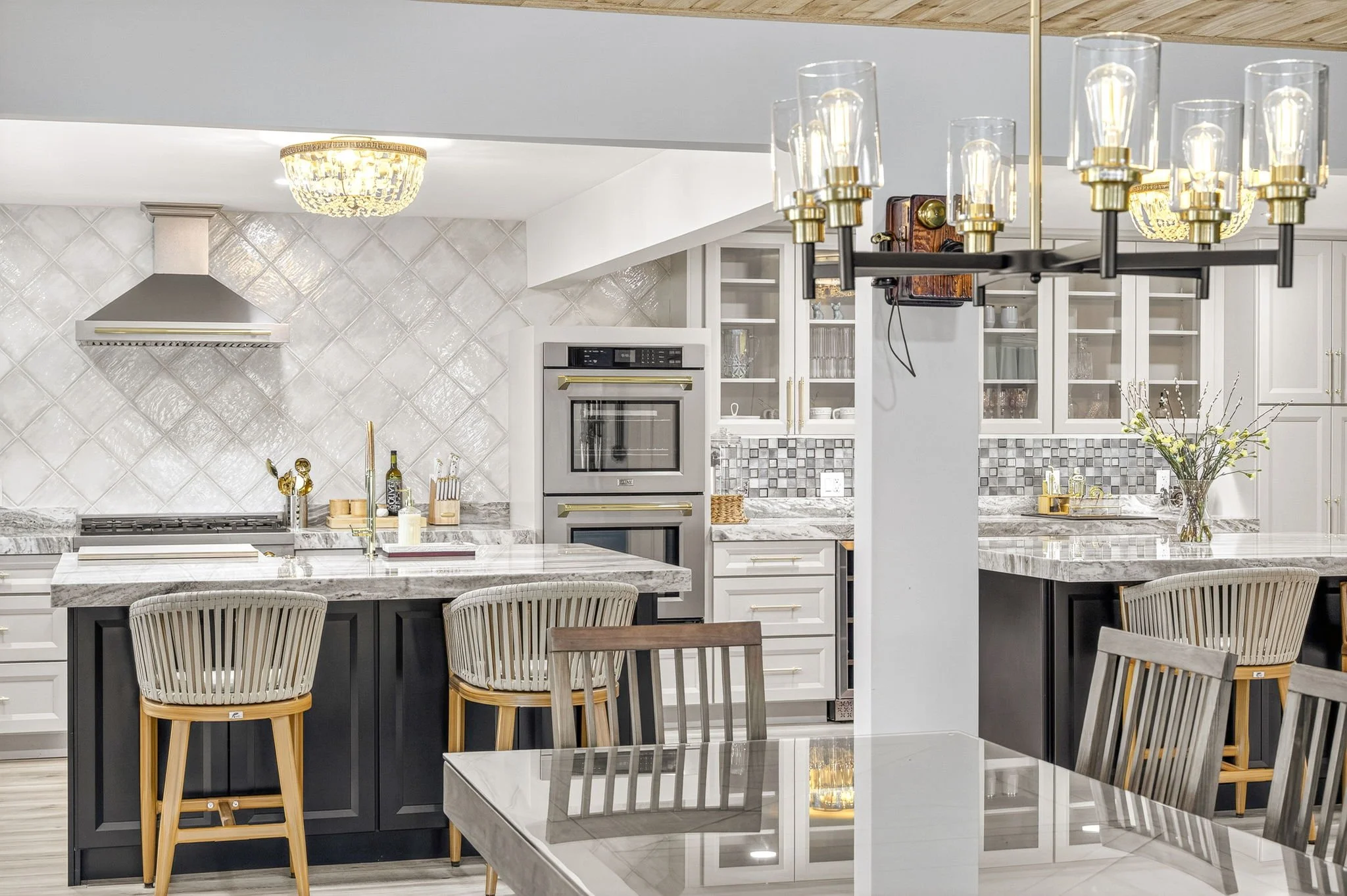 Interior photo of a modern kitchen with marble countertops, black chandelier, and two-tone cabinetry by VisionBoost Studios.