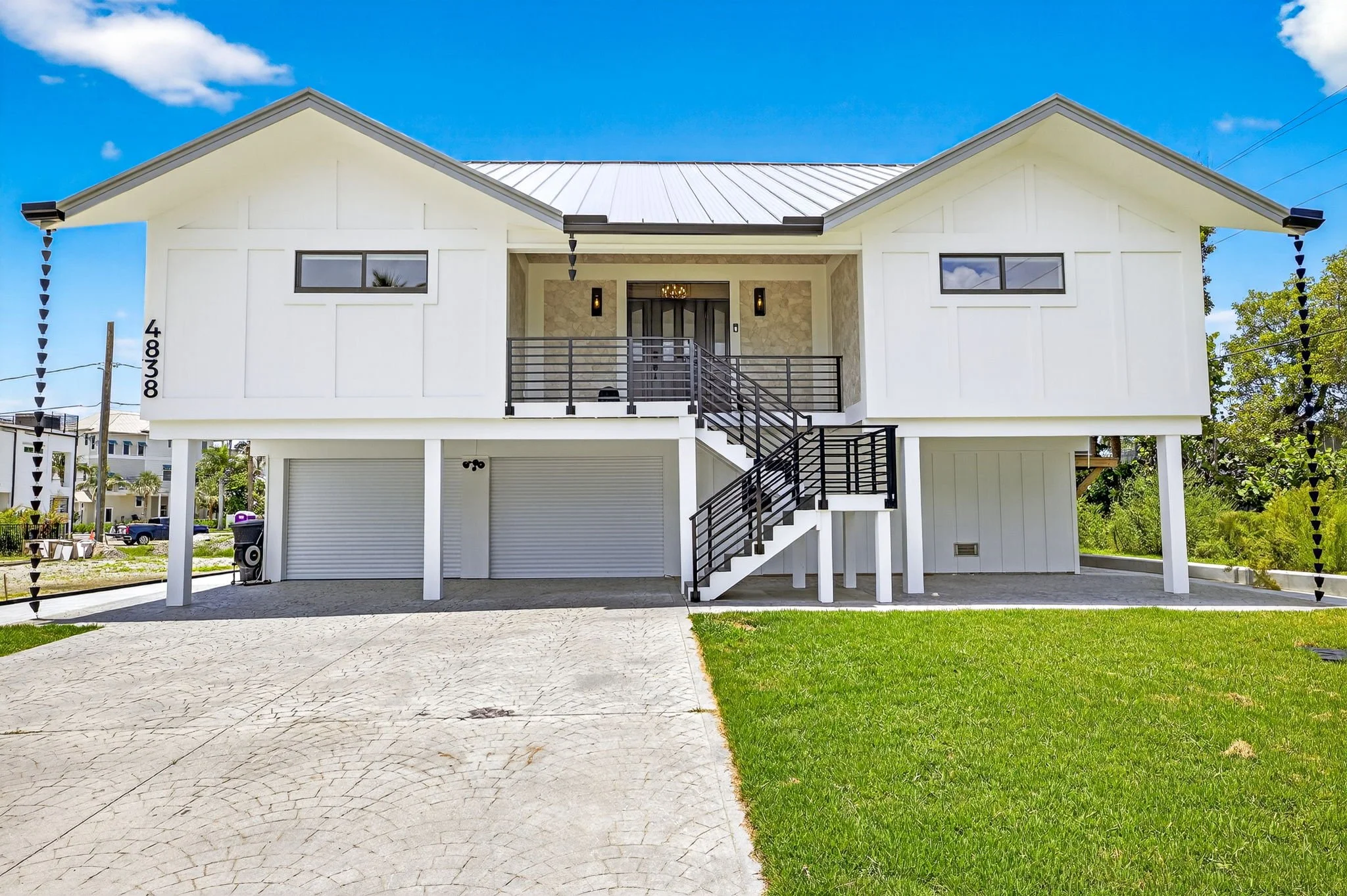 Cinematic exterior photo of a modern two-story home by VisionBoost Studios — white façade, black railings, front driveway.