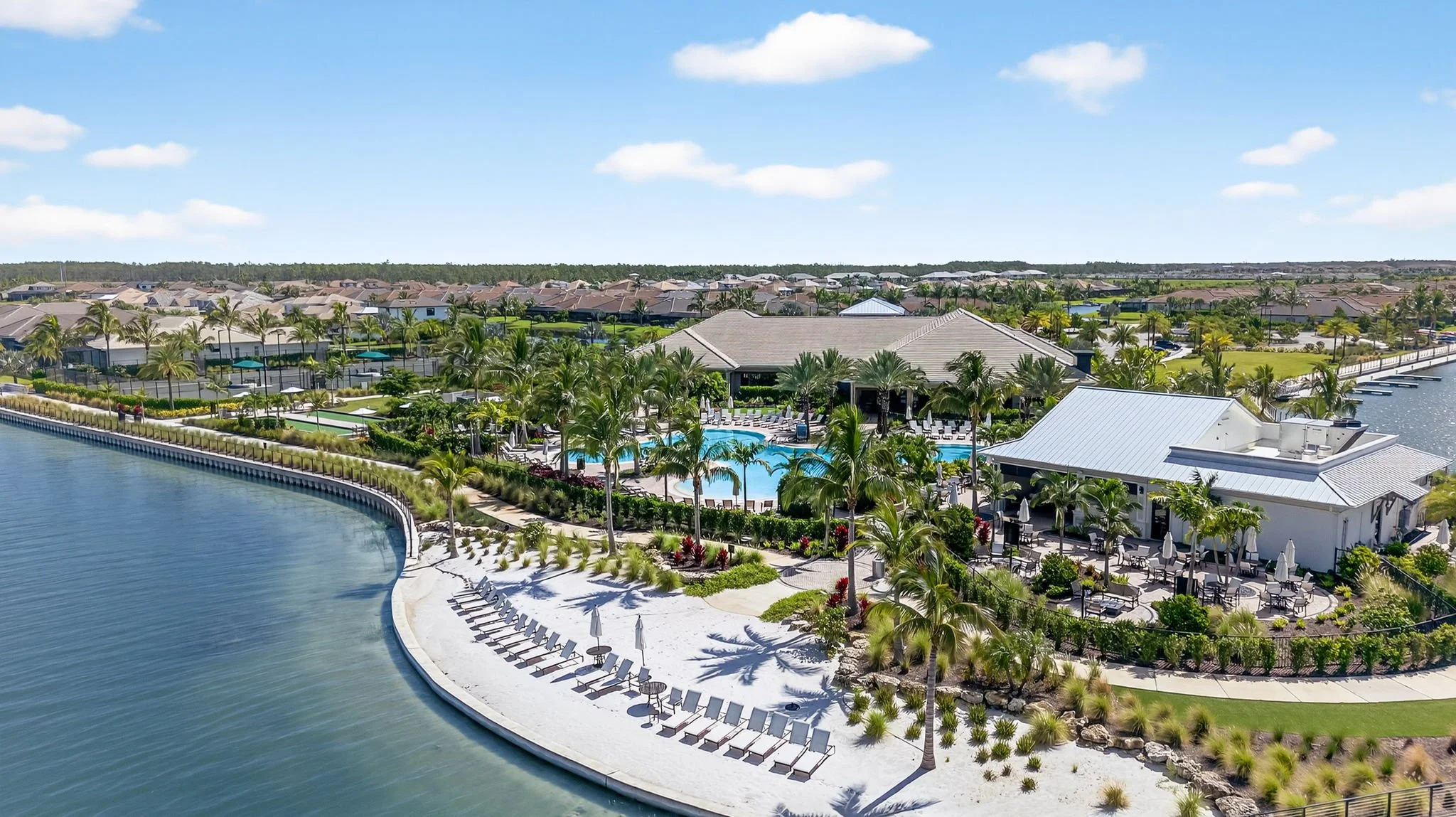 Drone photo by VisionBoost Studios of a luxury resort with pool, beach access, and waterfront properties surrounded by palm trees.
