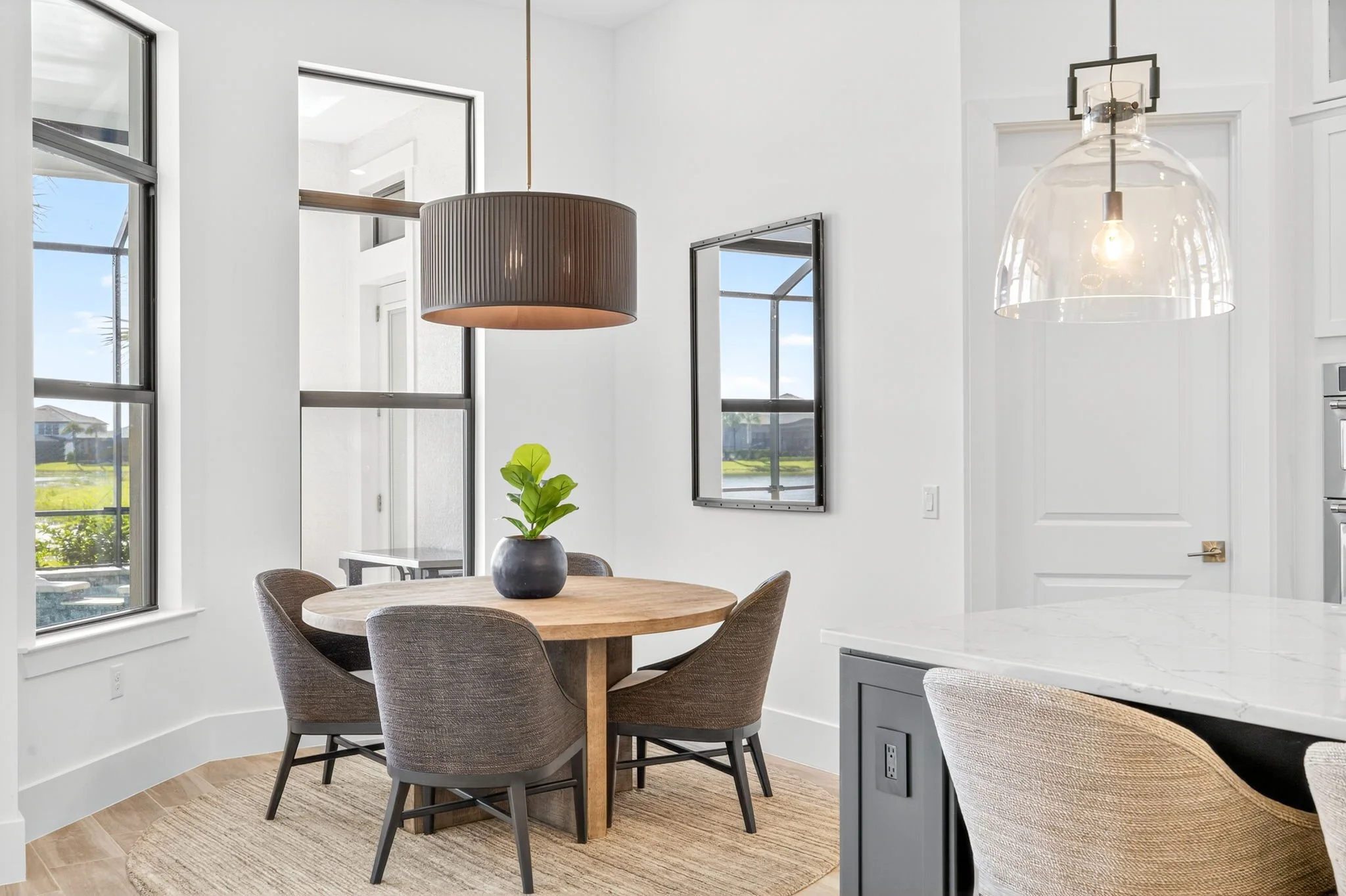 Staged dining area with wooden table, upholstered chairs, and bright windows captured for real estate listing by VisionBoost Studios.