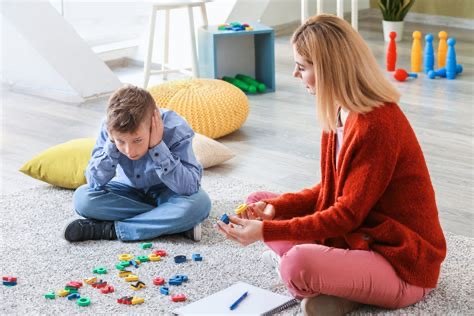 Woman and child playing with colorful game pieces on the floor in a bright room.