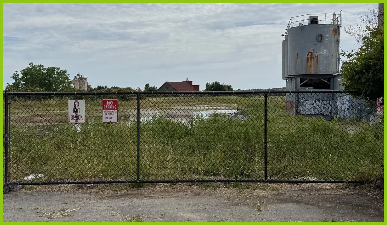  A bit farther down on the other side, a fenced lot holds a rotting tanker and standing water. 