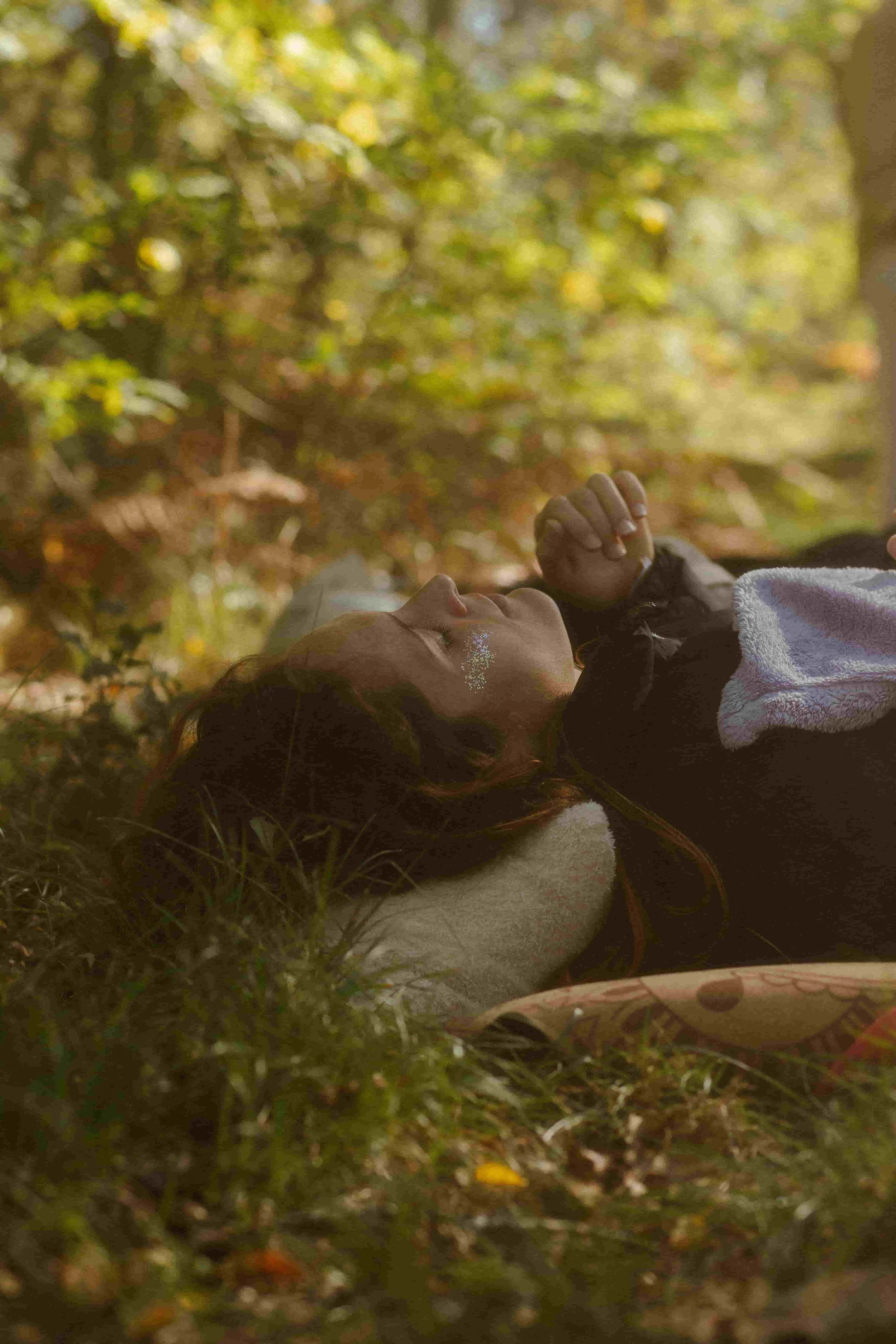 Laura, praticienne en bains sonores, guidant un bain sonore géant en forêt lors d’un festival, sous des lumières suspendues colorées.