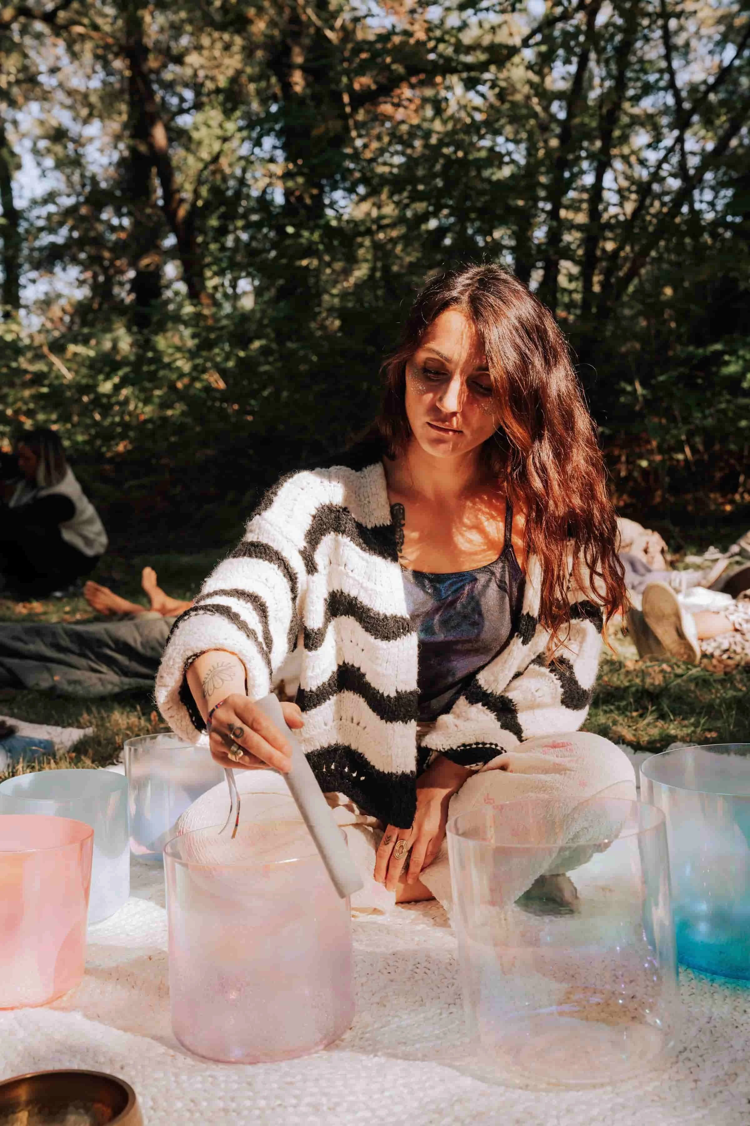 Laura, praticienne en bains sonores, guidant un bain sonore géant en forêt lors d’un festival, sous des lumières suspendues colorées.