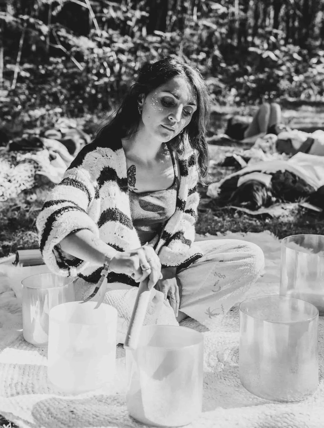 Laura, praticienne en bains sonores, guidant un bain sonore géant en forêt lors d’un festival, sous des lumières suspendues colorées.