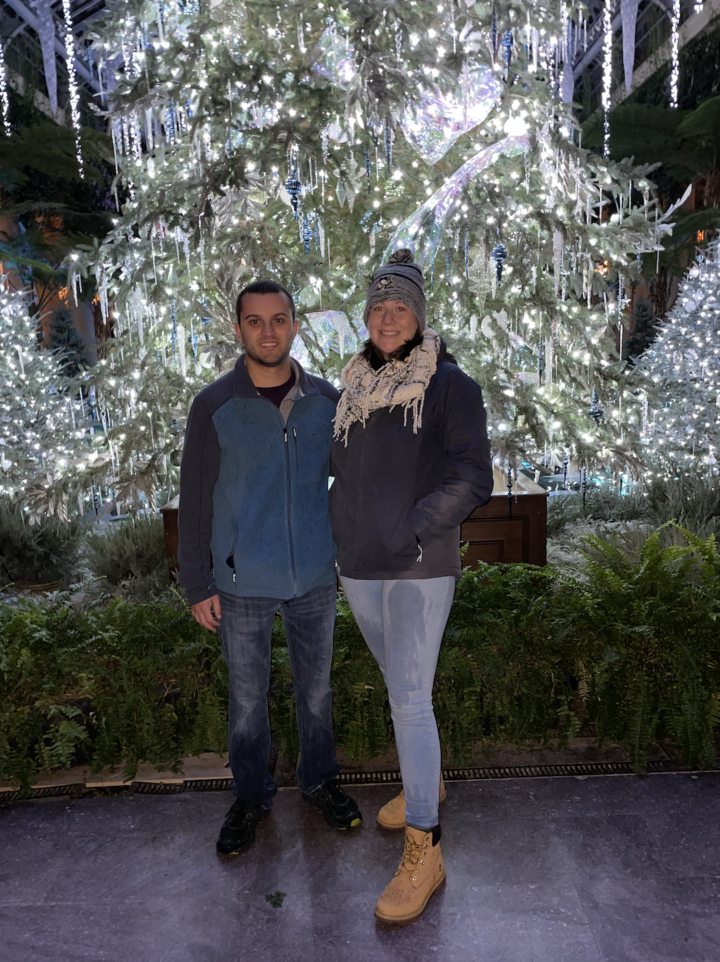 Two people smiling in front of an elaborately decorated Christmas Tree