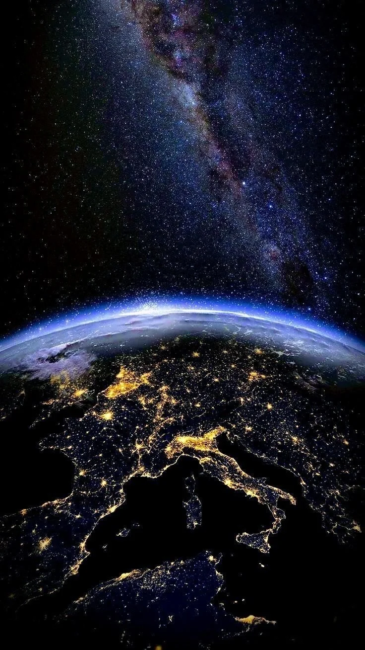 Une vue de l'espace montrant la Voie lactée dans le ciel et la Terre vue de l'espace avec l'Europe, affichant des lumières urbaines la nuit.