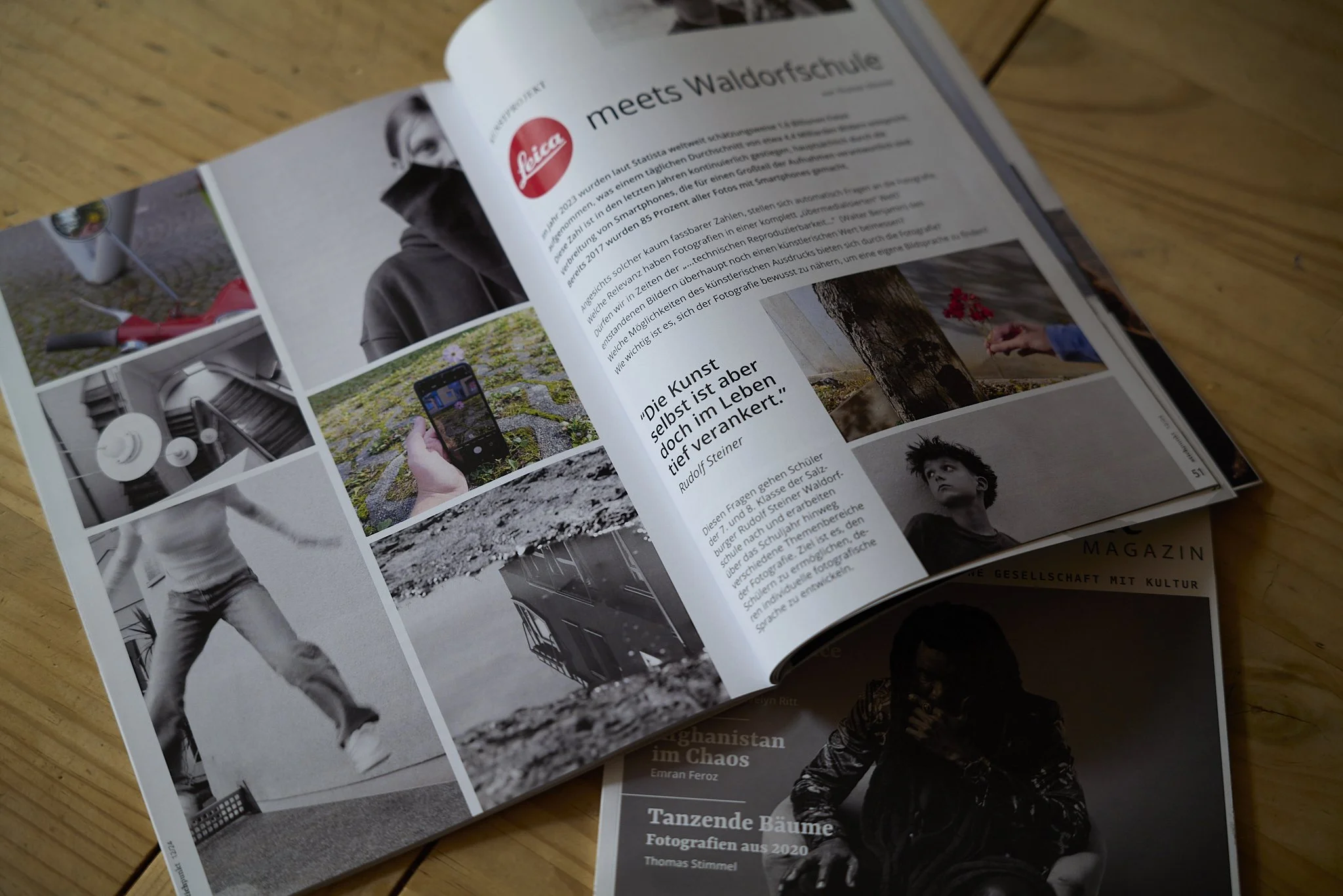 Offener Zeitschriftenartikel über das Projekt Leica Meets Waldorfschule mit Fotos von Menschen und Landschaften, Text in Deutsch, auf einem Holzschreibtisch gelegt.