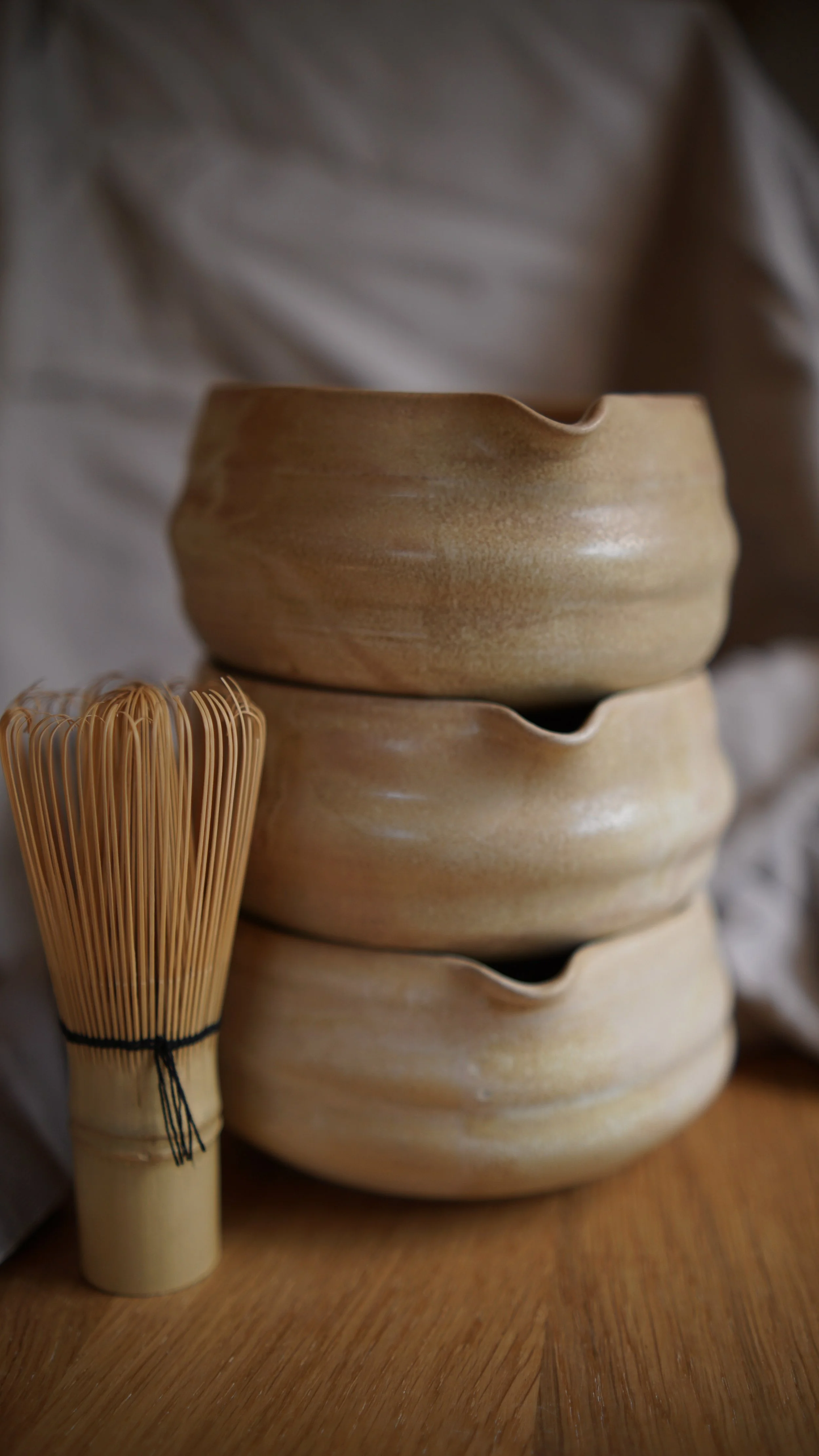 Zwei Matchaschalen in der sandfarbenen Glasur Düne der Bremer Keramikerin mithändengemacht. Daneben ein Chasen Matchabesen.