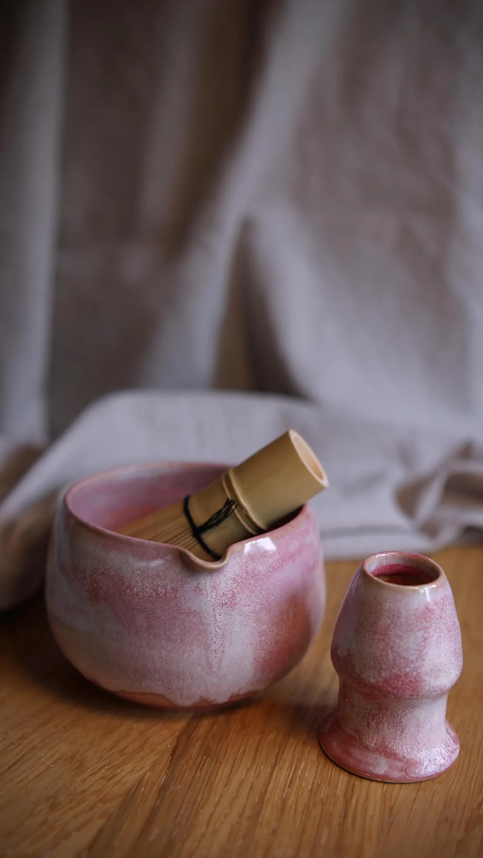 Ein Matchabesen liegt in einer handgemachten Keramik Matchaschale mit rosa Glasur