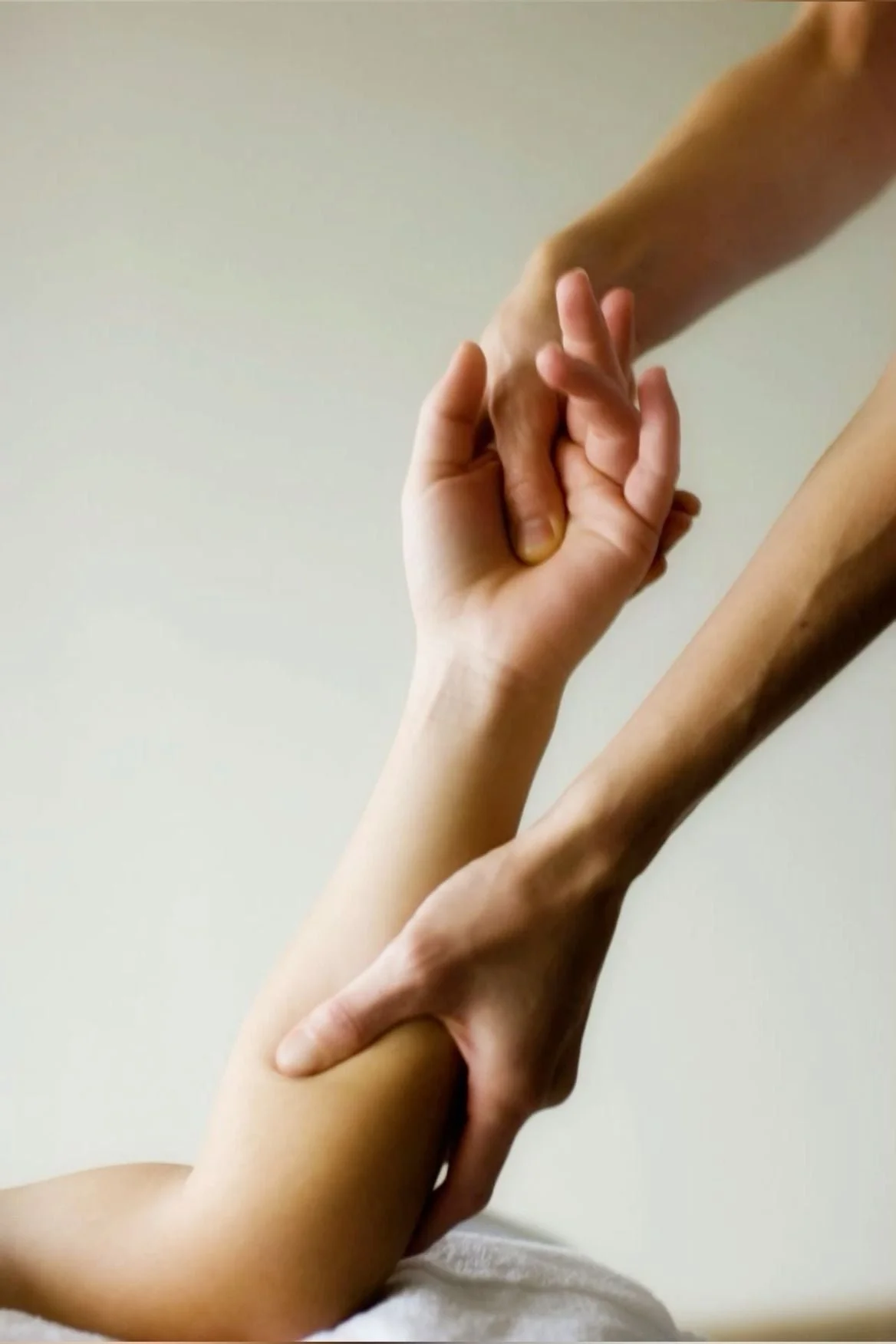 A person receiving a massage focusing on the arm and hand, with the massage therapist's hand applying pressure.