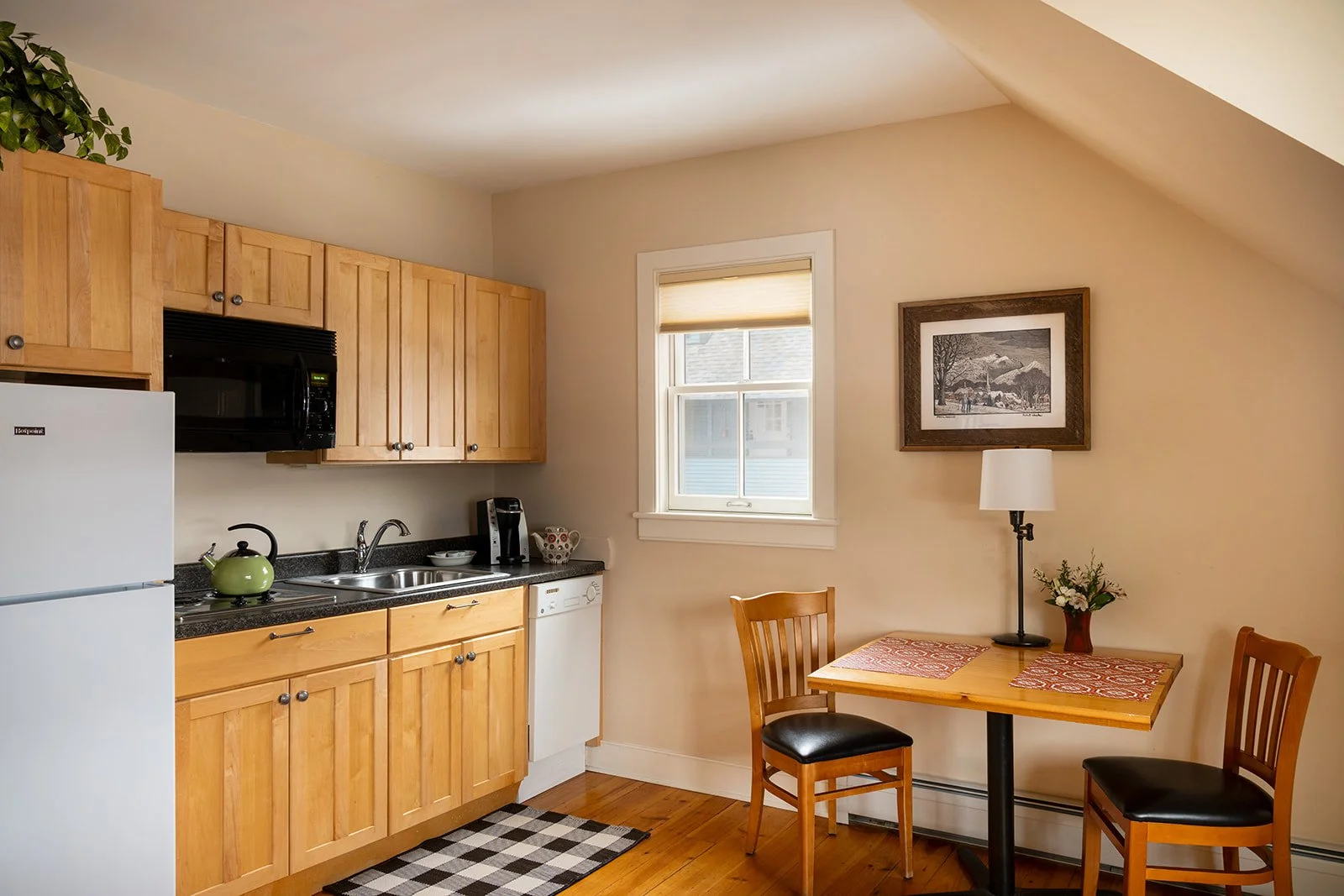 Kitchen and dining area in Butler's Hideaway Stowe VT with wood cabinetry and table for two