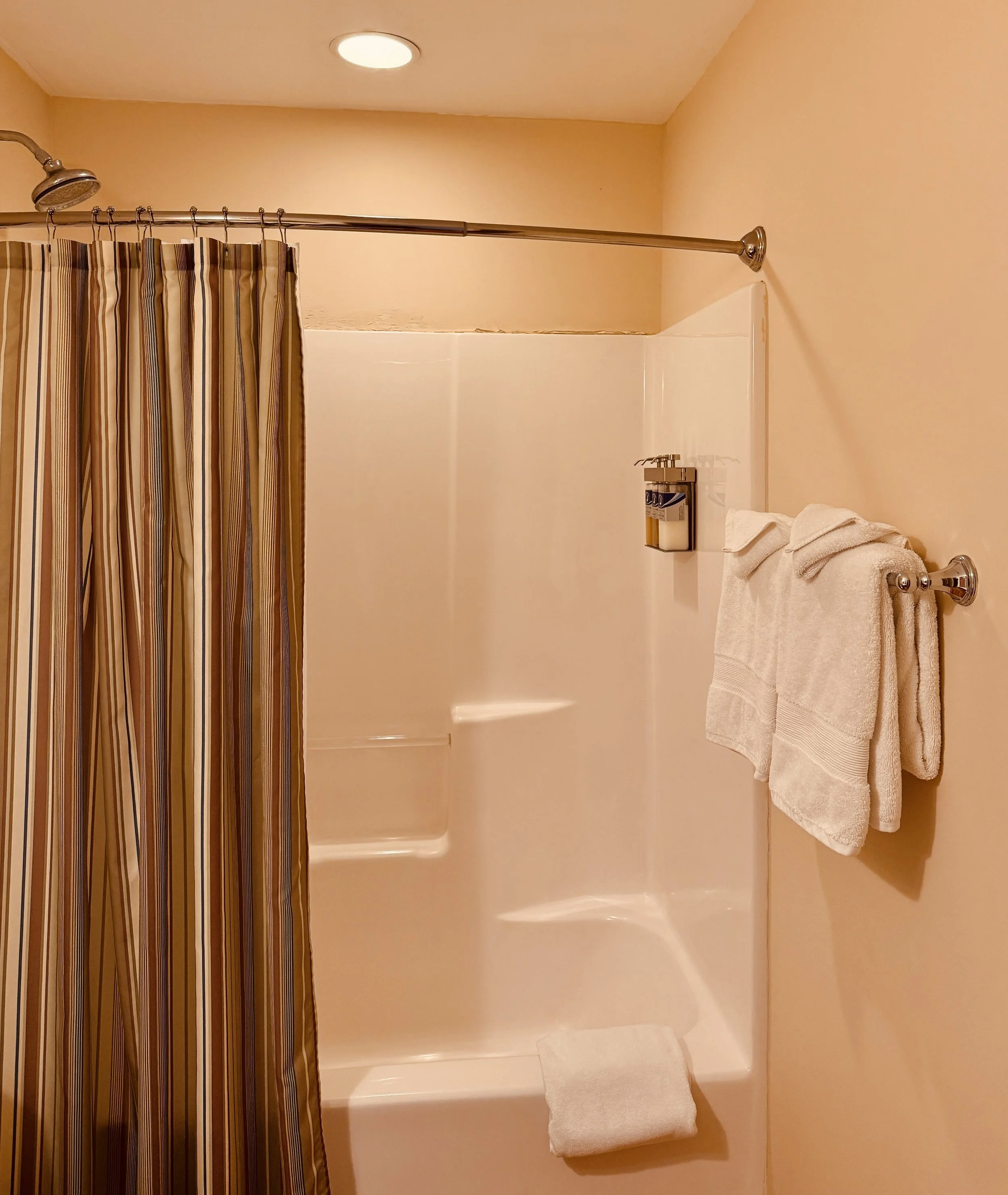 Shower in Butler's Hideaway bathroom with tub and curtain in a simple, functional layout