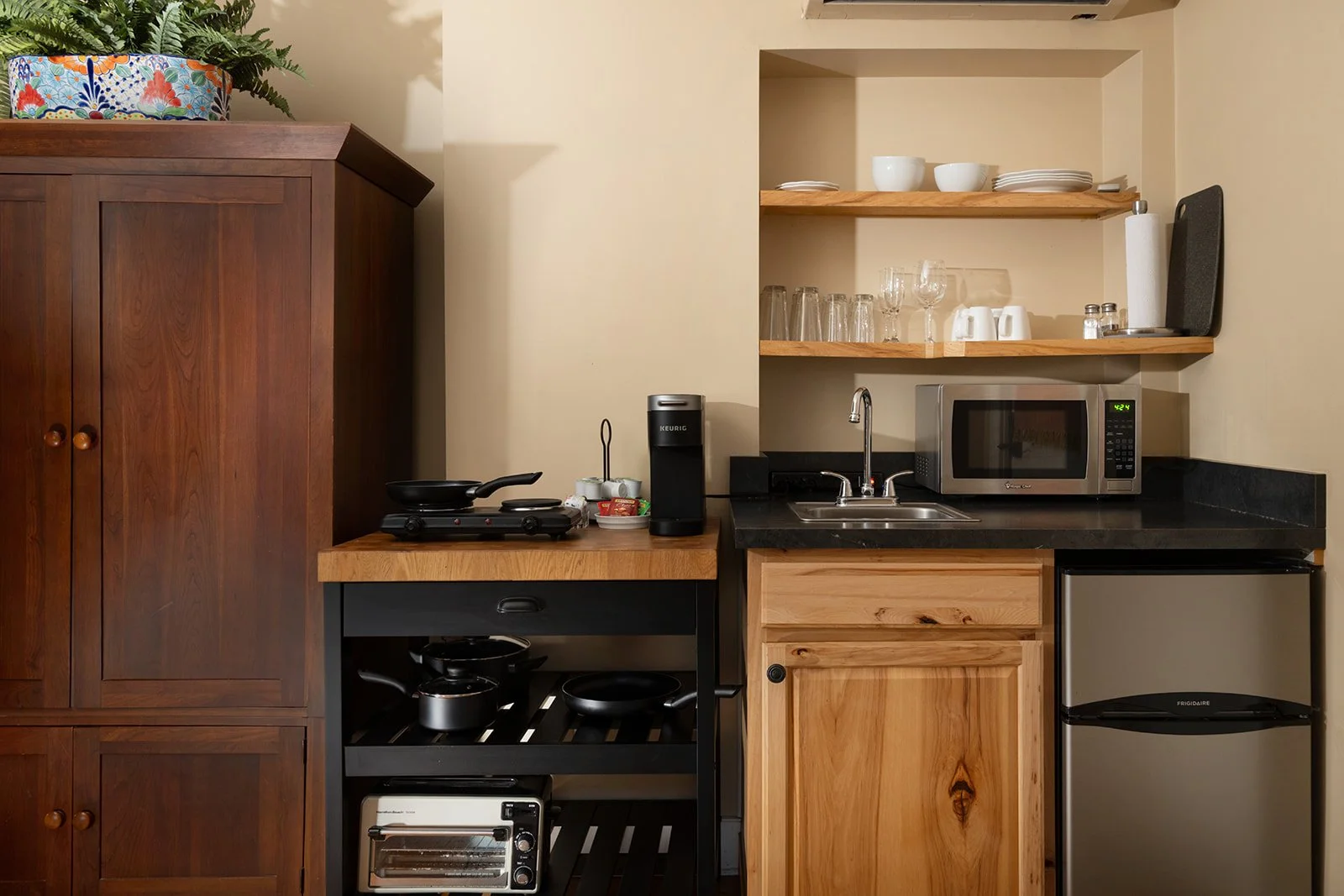 Kitchenette in The Lounge Stowe VT with compact appliances, wood cabinetry and open shelving