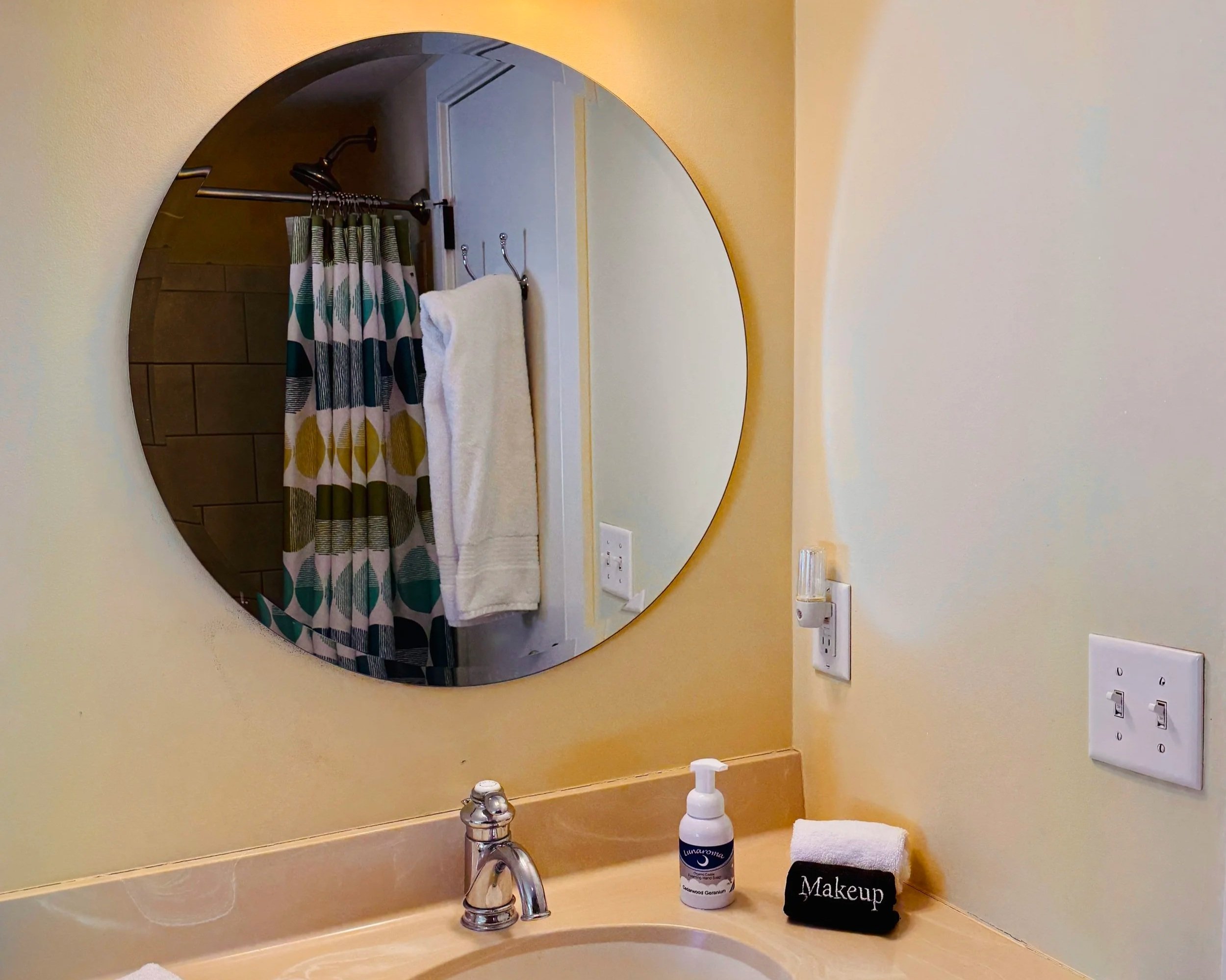 Bathroom in Orion's Retreat with round mirror, clean vanity and simple modern fixtures
