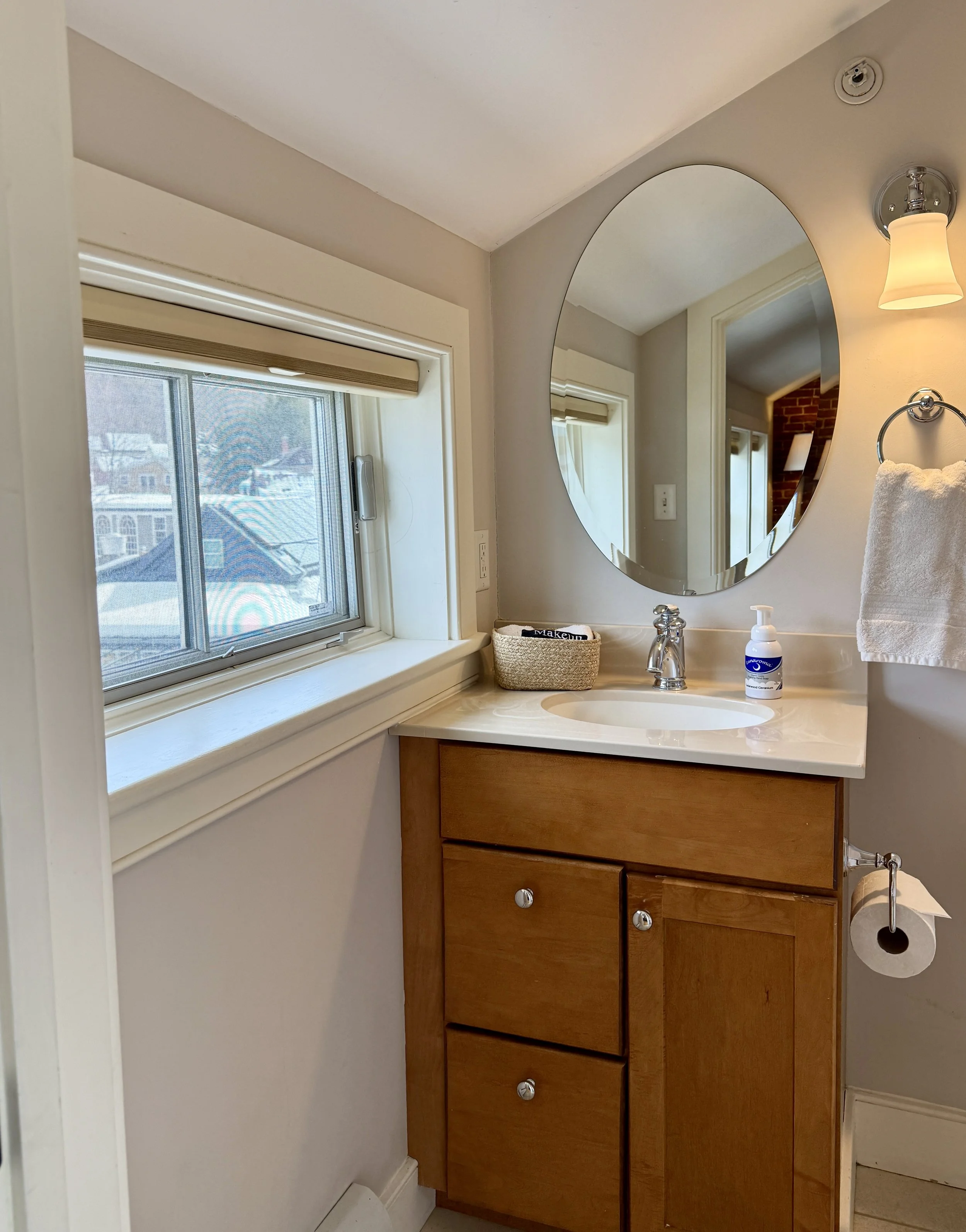 Bathroom in Murphy's Studio featuring clean vanity, round mirror and natural light from the window