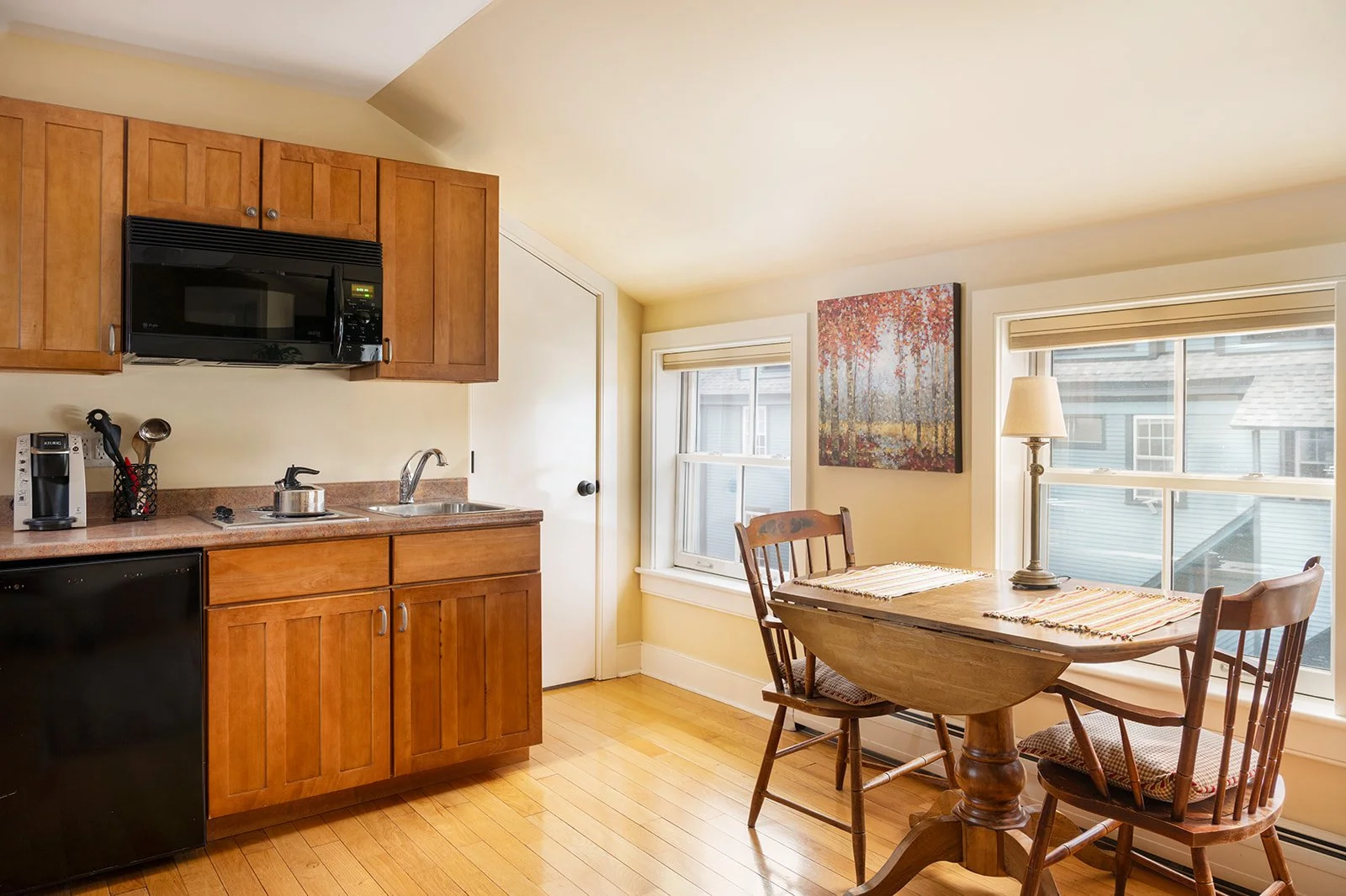 Kitchenette and dining area in Zoe's loft Stowe Vermont with wood cabinetry and table for two