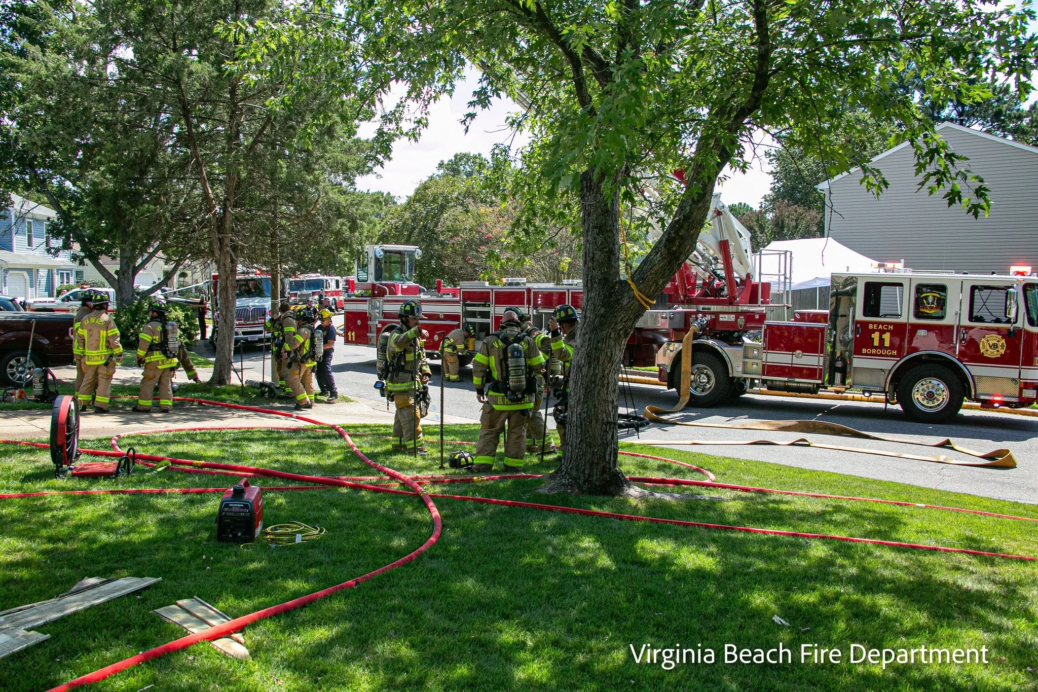Virginia Beach fire department firefighters responding to an emergency with a large red fire truck parked on the street.