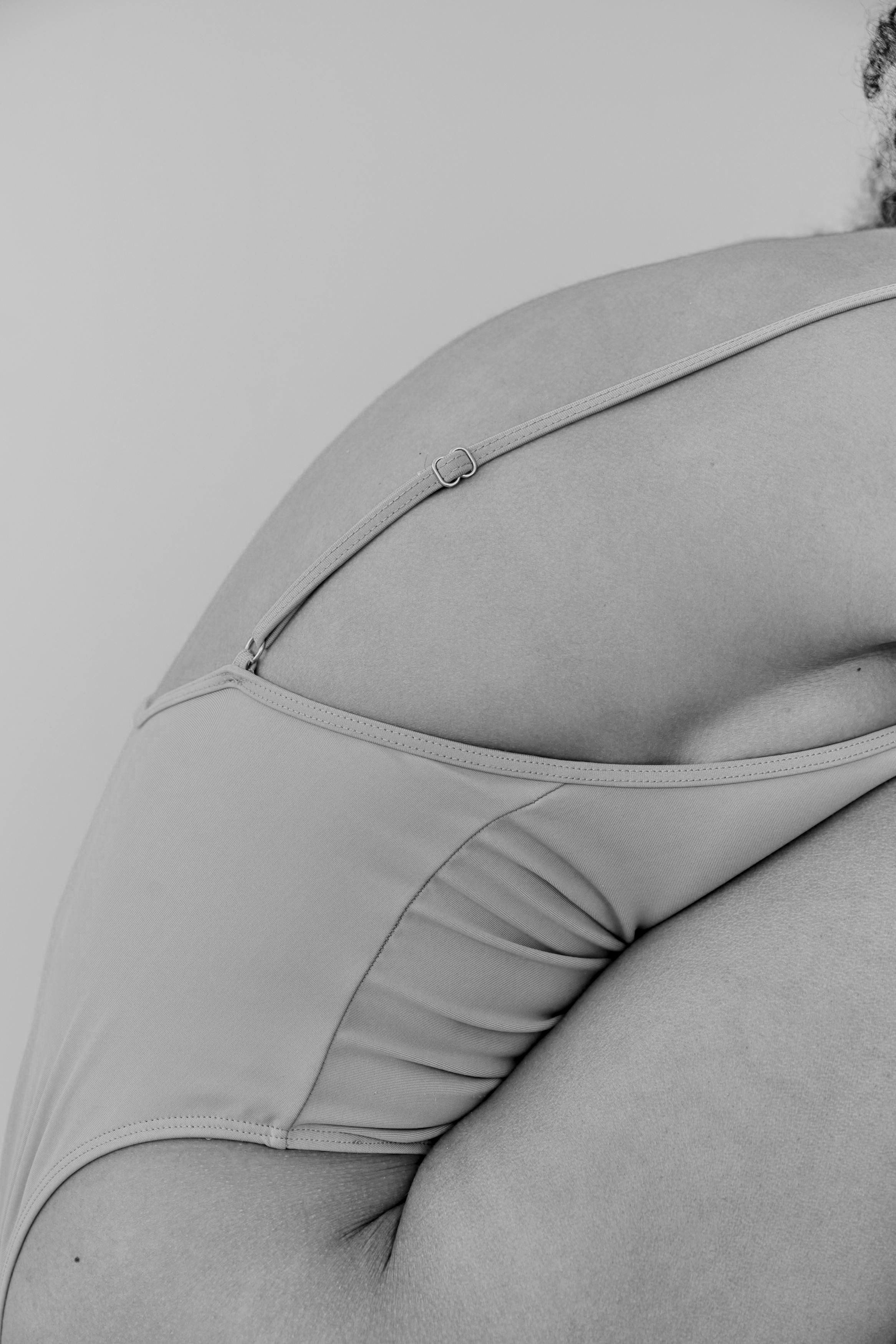 Close-up of a person's hip and side, wearing high-cut underwear with a zipper detail, in black and white.