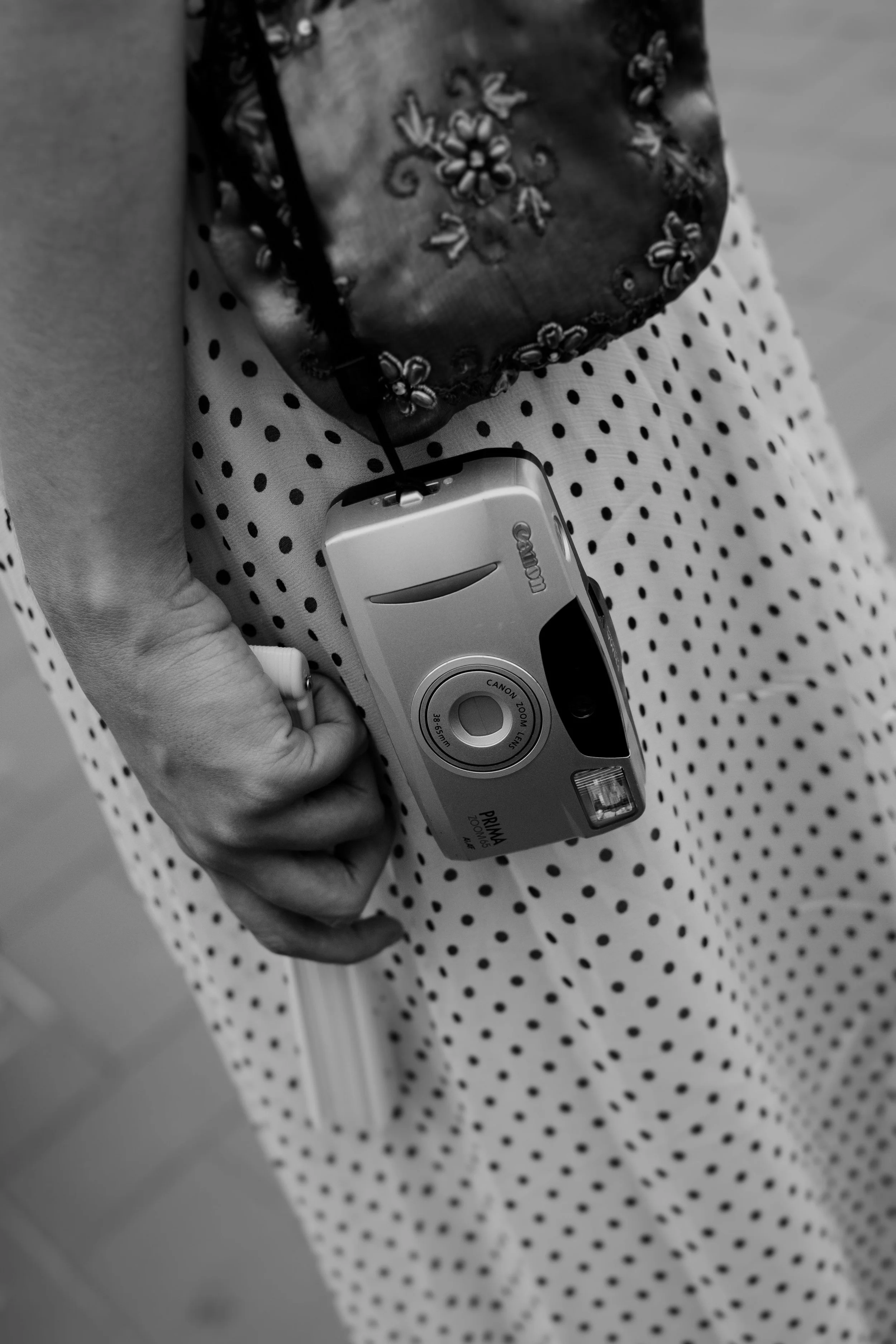 Close-up of a hand holding an analog camera representing an artistic wedding photography approach