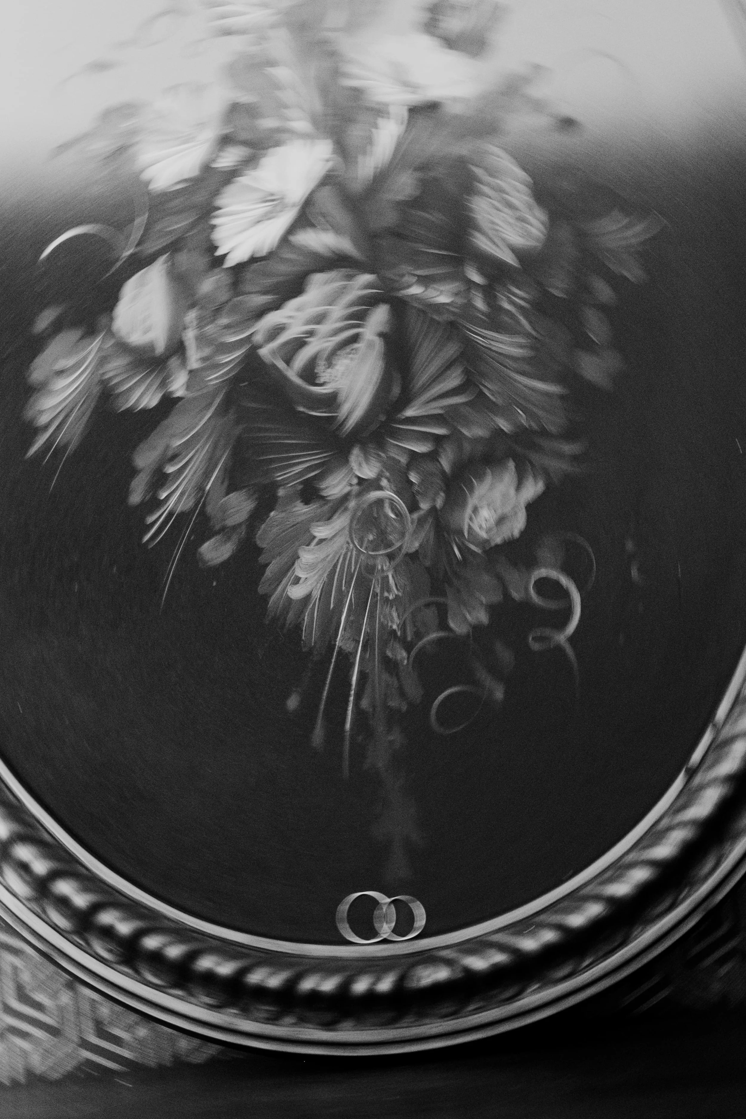 Abstract black and white photo of a vintage floral painting with intentional motion blur, framed in an ornate oval frame, captured by Carlos Mendes Photography.