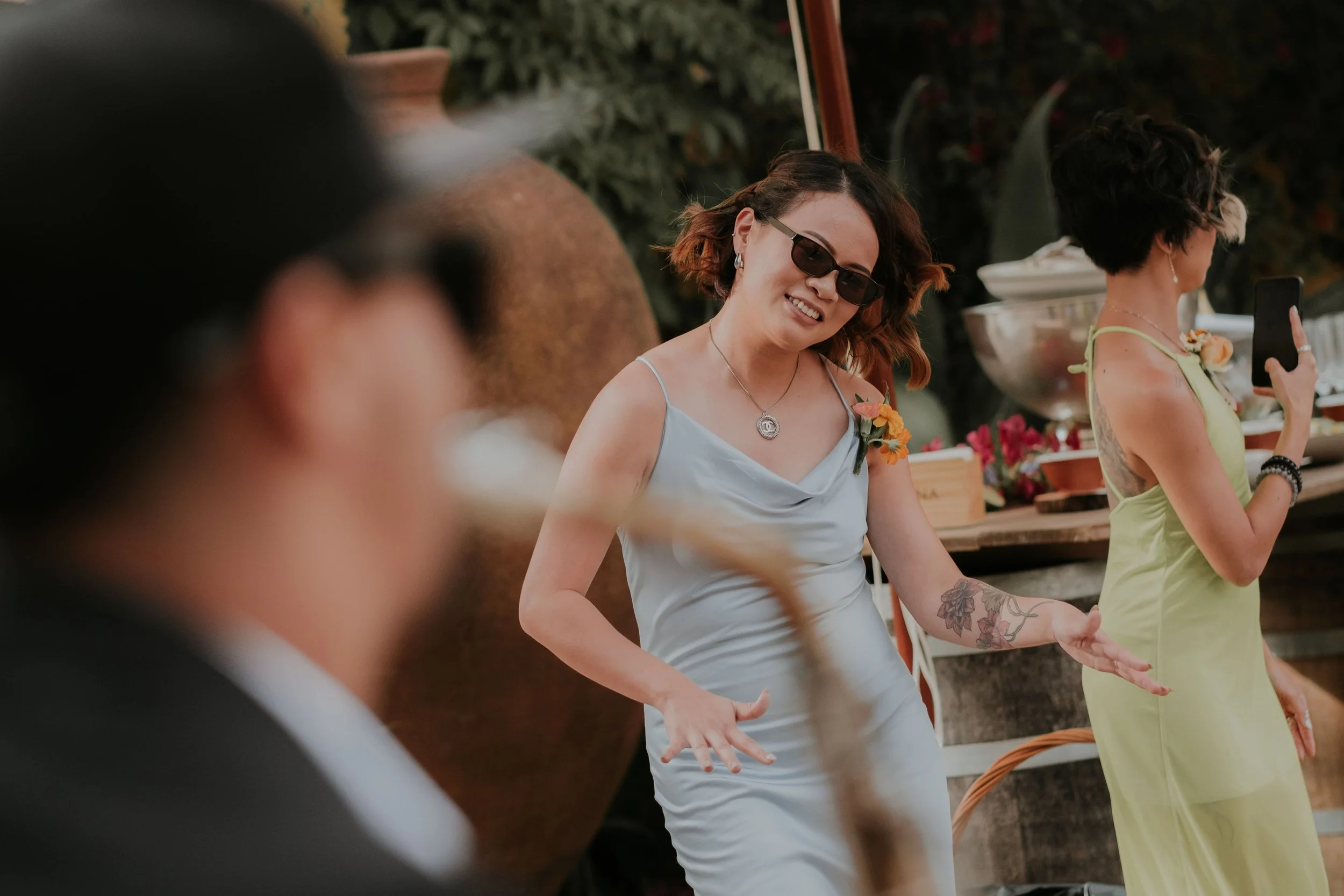 Wedding guest in a light blue dress joyfully dancing to live saxophone music during the cocktail hour at an outdoor wedding celebration. Captured by Carlos Mendes Photography.