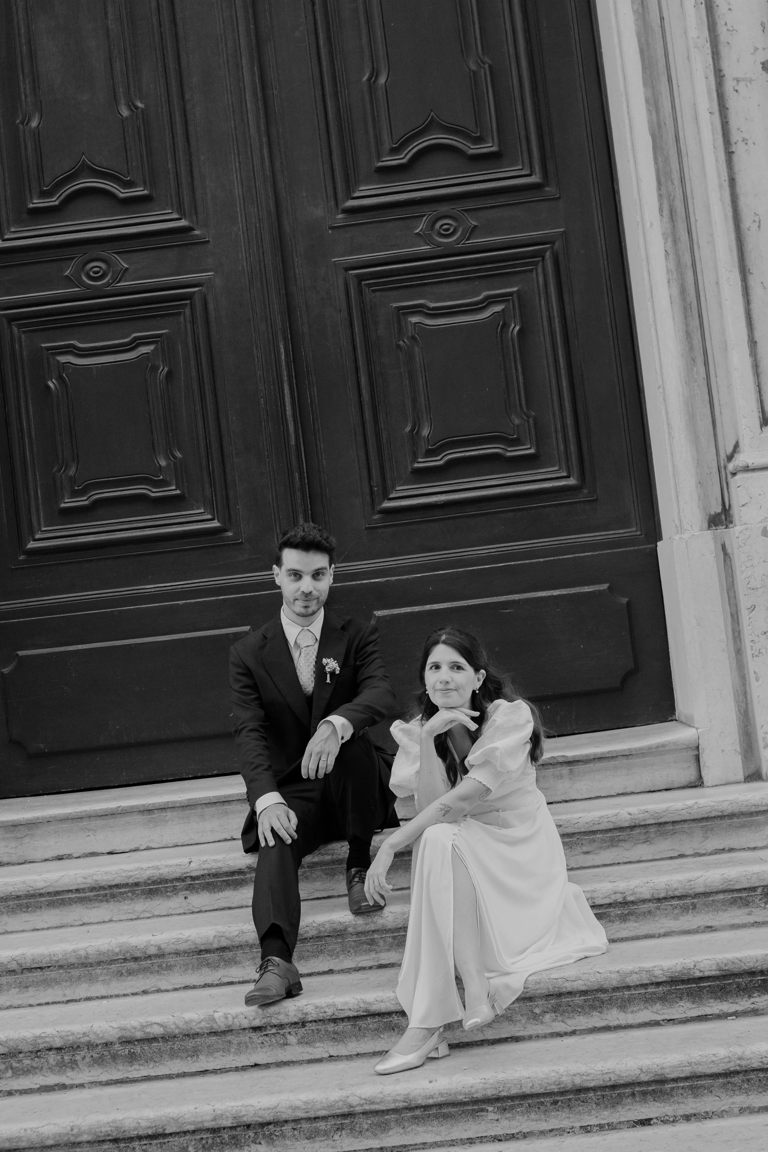 Bride and groom sitting on architectural steps during a wedding in Portugal