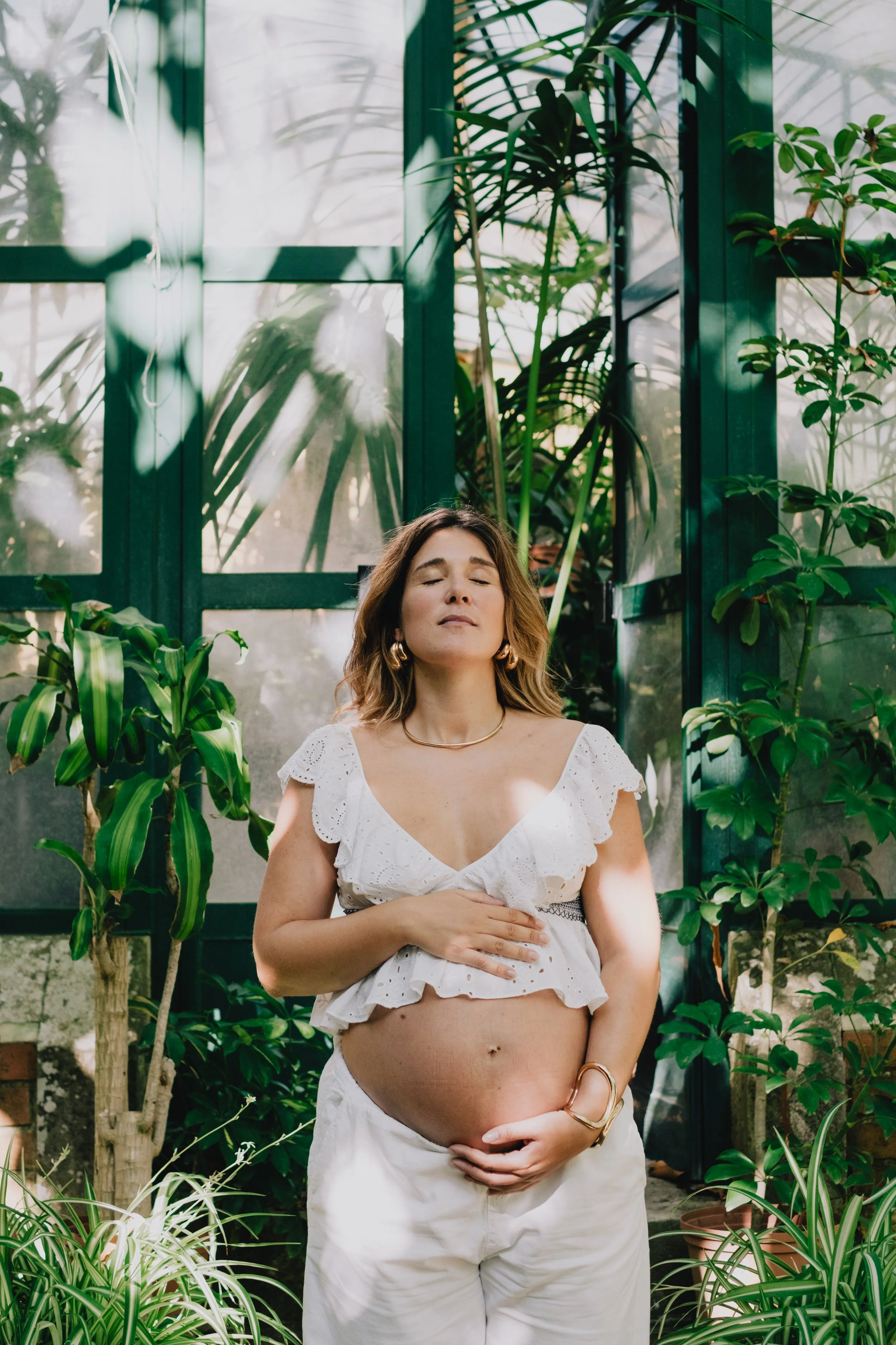 Pregnant woman during a maternity session surrounded by greenery in natural light