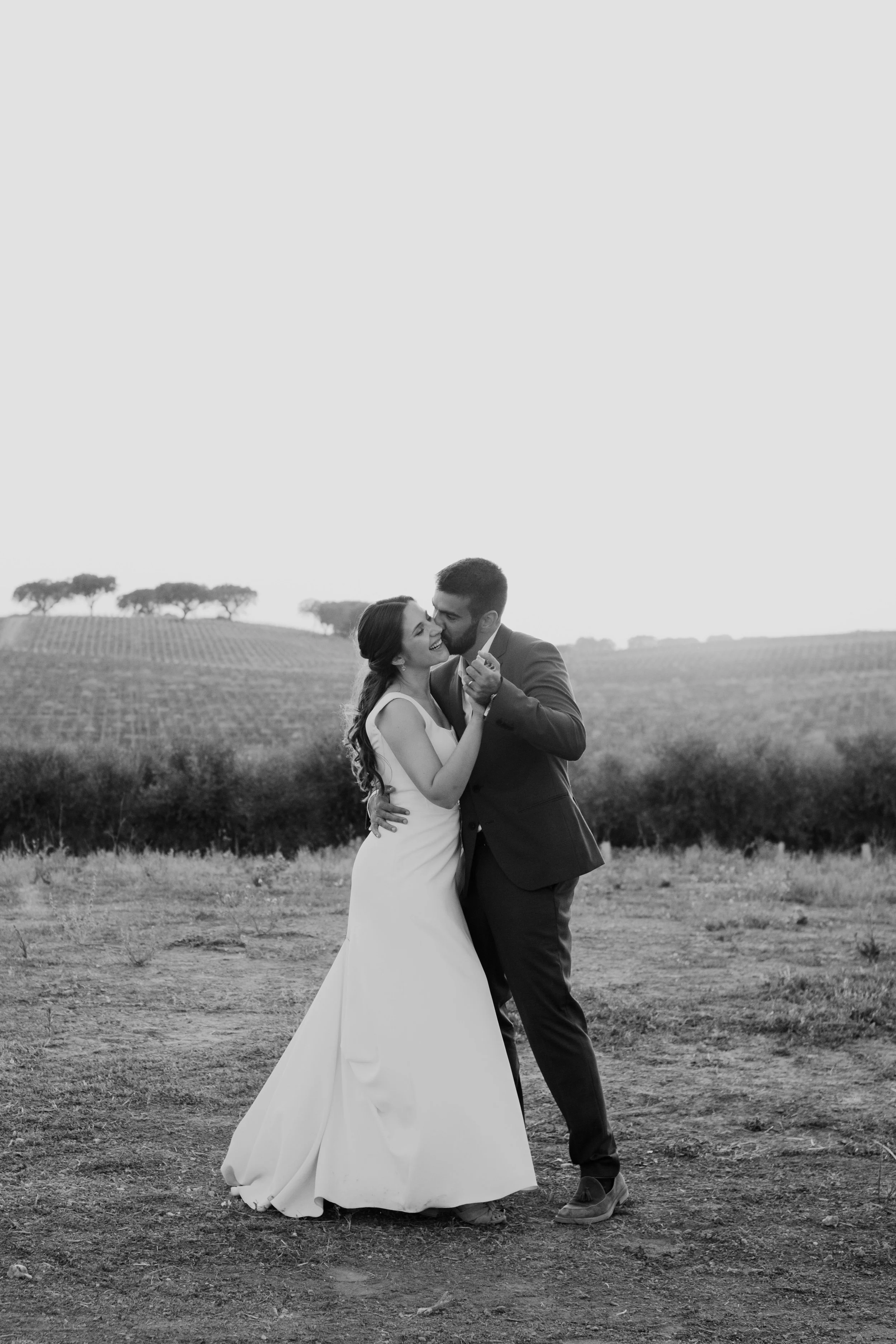 Bride and groom sharing a romantic moment in an open field in Portugal captured in black and white